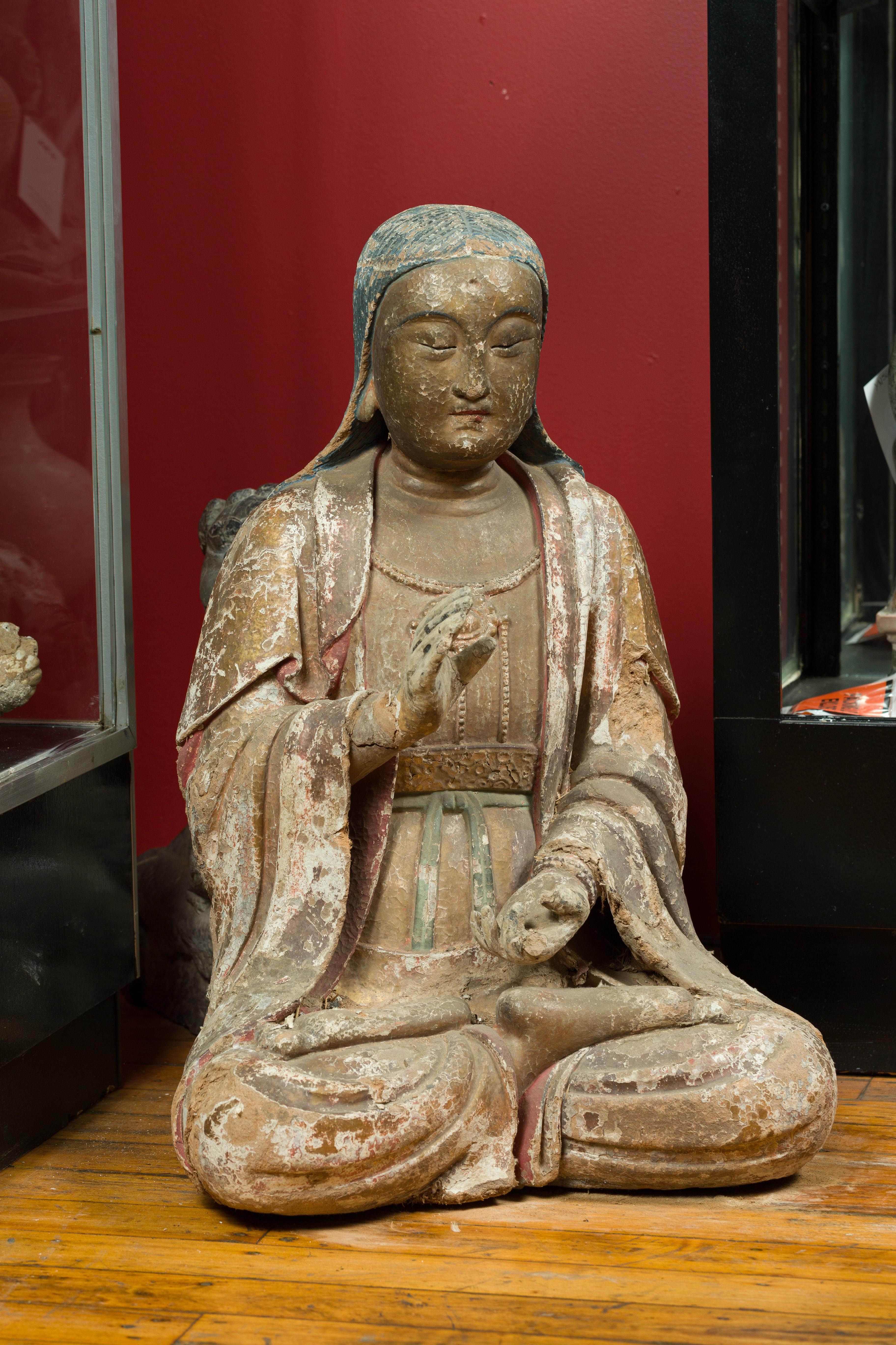 A Chinese Song Dynasty period painted stucco sculpture of Guanyin, Bodhisattva of Compassion, circa 960 to 1279. Created in China during the Song Dynasty, this seated sculpture depicts Guanyin the Bodhisattva of Compassion, wearing a dress, a coat
