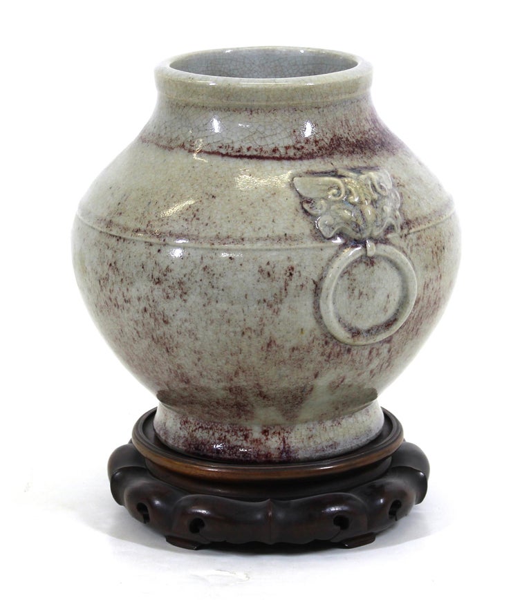Chinese Qing style celadon ceramic jar vase with lion head handles and crackle glaze, on carved wood stand.