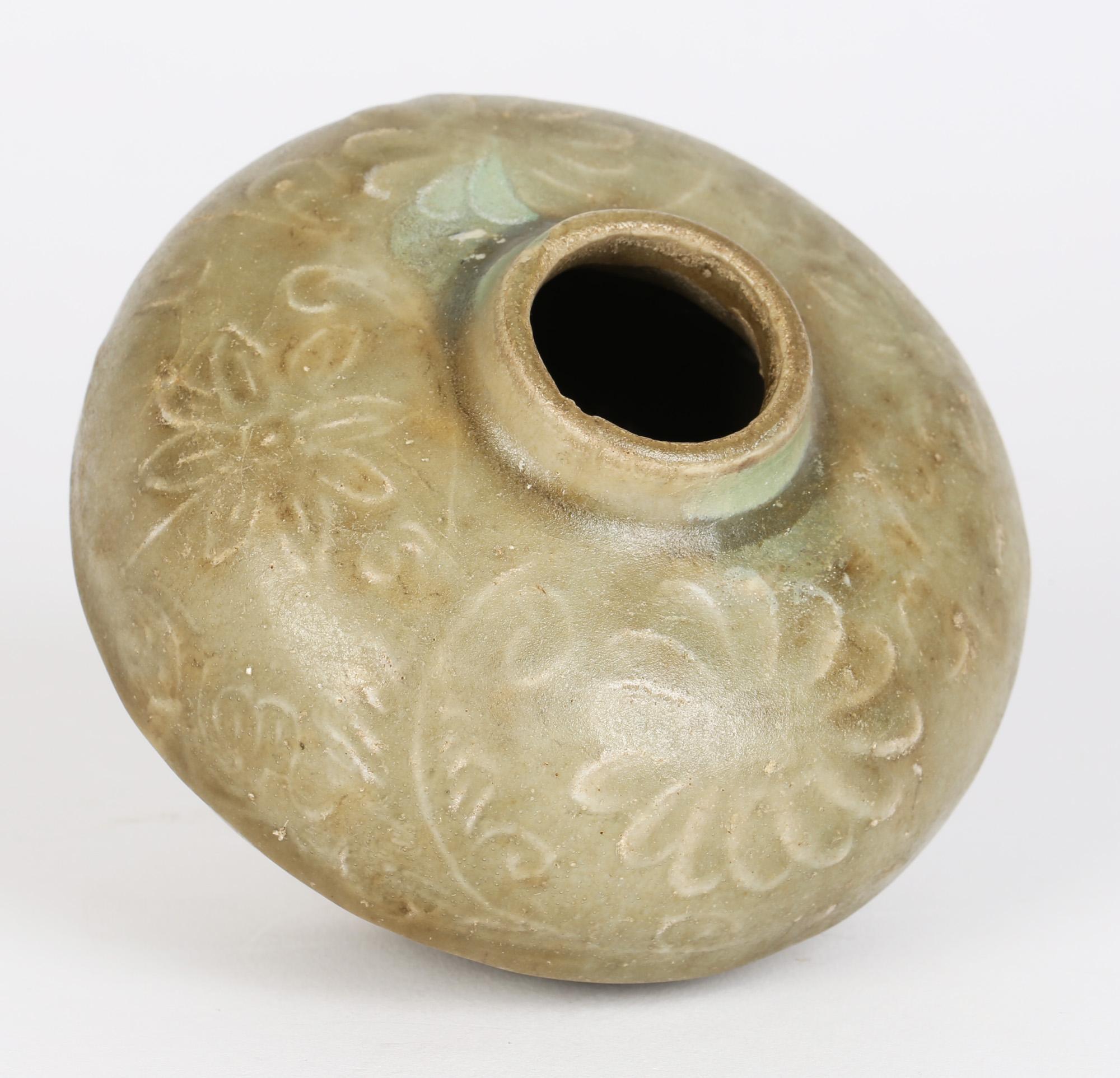 A good antique Chinese Song/Yuan Dynasty floral molded Longquan celadon glazed jar dating between 1127 and 1368. The jar of squat rounded shape stands on a narrow rounded unglazed foot with a narrow short funnel raised opening. The body is