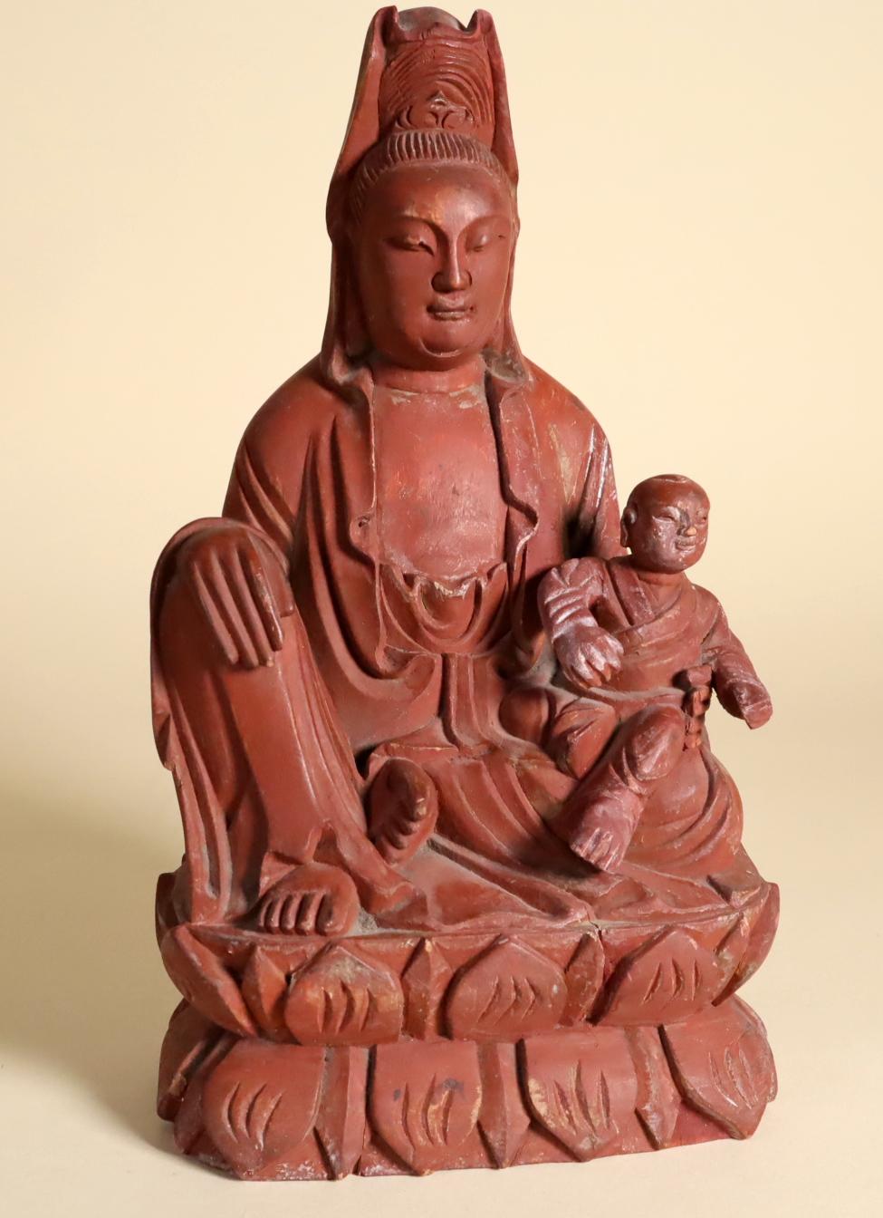 A Chinese wood figure of Songzi Guanyin (Guan Yin, or Quan Yin, or Songzi Niangniang). Shown seated in lalitasana (pose of ease) with an animated boy seated on her left leg. Her hair is dressed in a high topknot centered by a lotus bud and covered