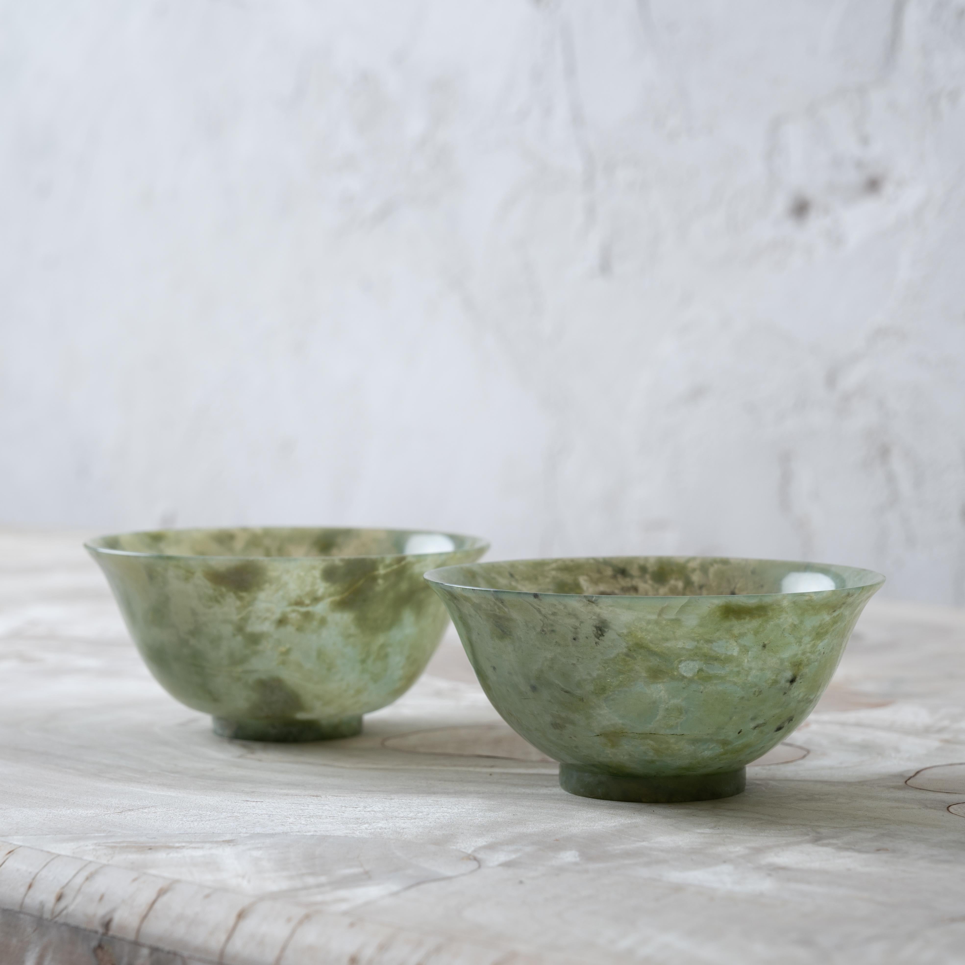 A pair of Chinese spinach jade bowls, circa 1920s. 

4 inches wide by 1 ¾ inches tall 

