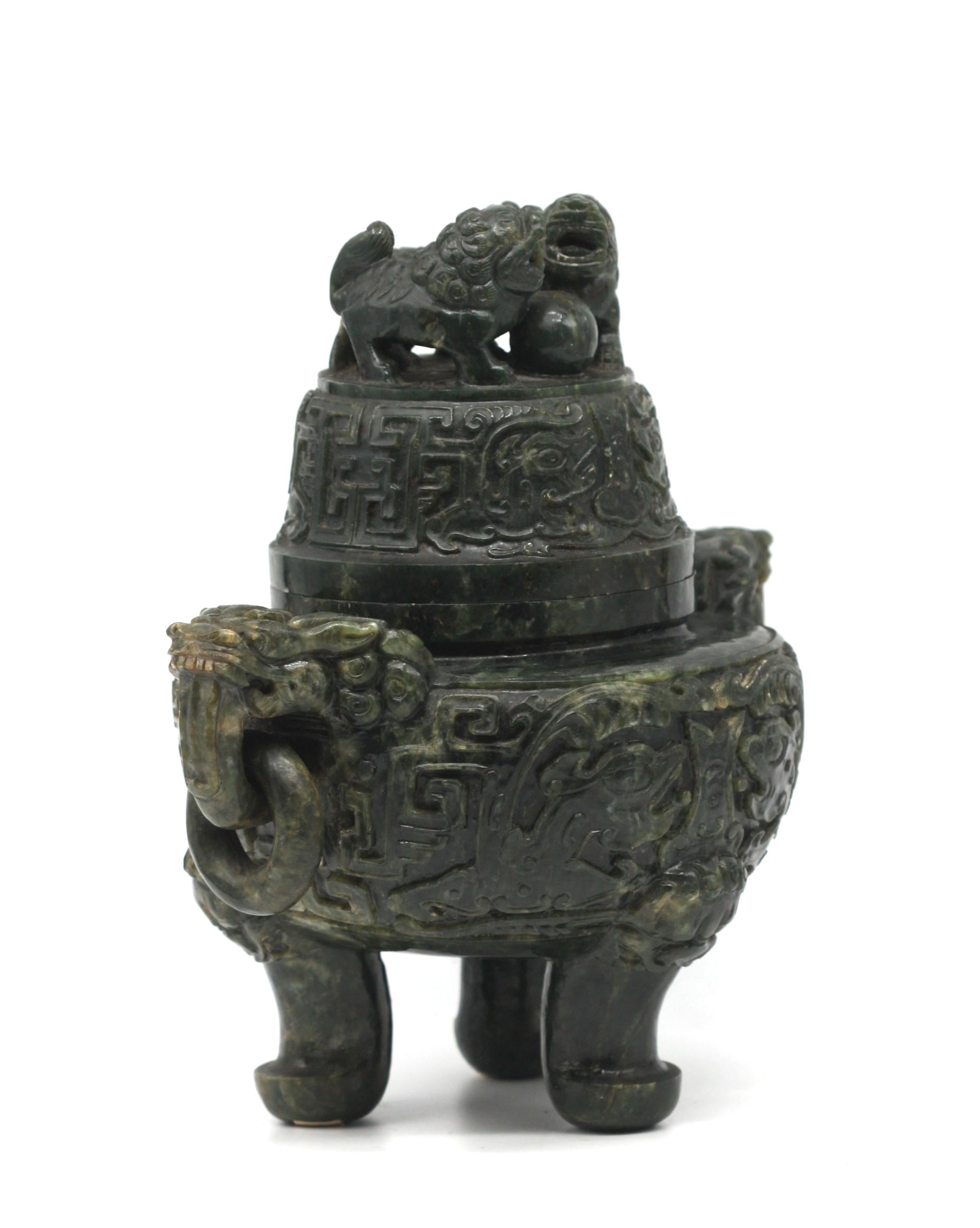 
Chinese Spinach Jade Covered Tripod Censor 
Depicting an archaic Bronze vessel, the circular body with projecting mask handles with loose rings, the body with make and scrolls in relief, on cylindrical legs with rounded feet, the domed cover carved