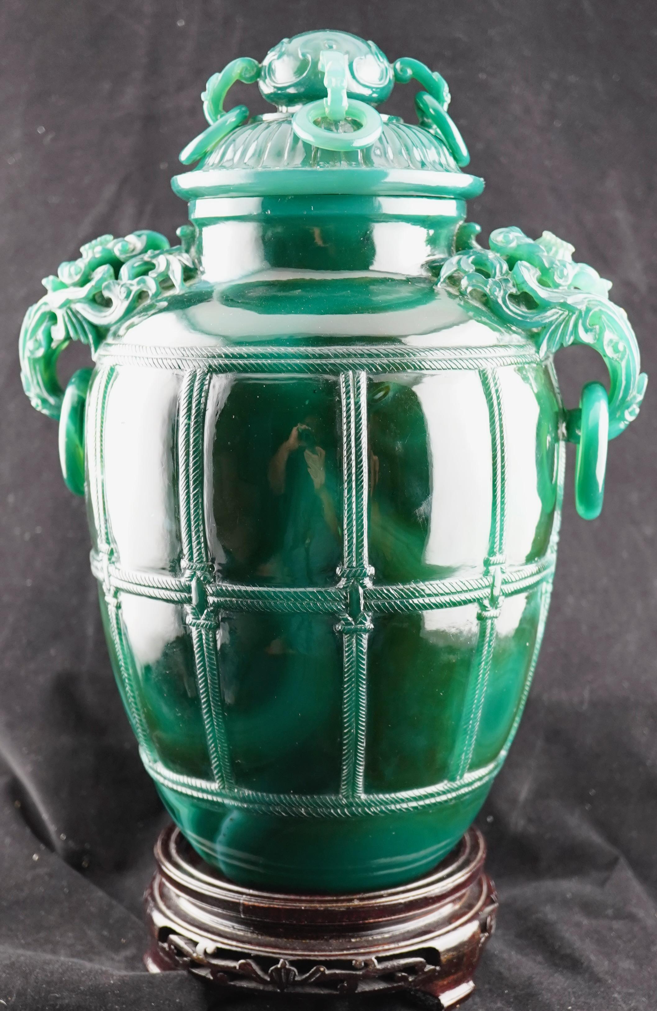 Chinese mid-century finely carved spinach jade covered vase. Executed in a form of a barrel secured by the ropes. Decorated with free floating rings and finely carved handles.. Handlw are in the form of dragon heads. The vase comes with 2