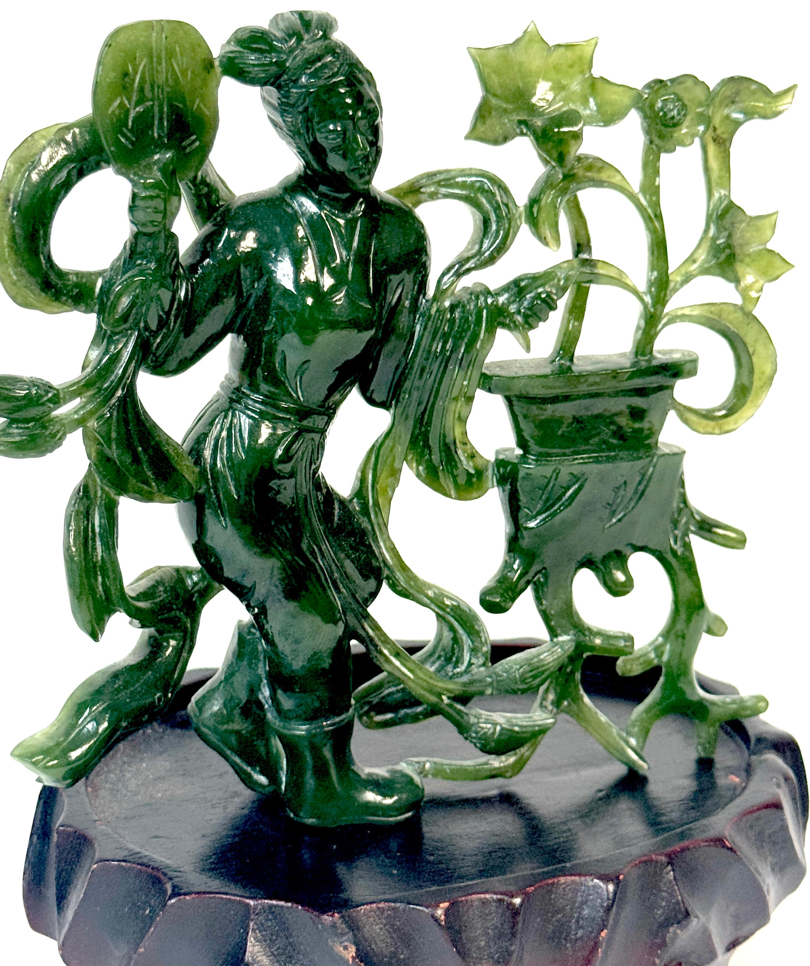 Chinese Spinach Nephrite Jade Immortal with Lotus, Mid-20th Century
Dimensions: 5” H x 5” W x 3” D (including base)

A finely carved Chinese figure of a celestial maiden, sculpted from a single piece of deep green spinach nephrite jade, permanently