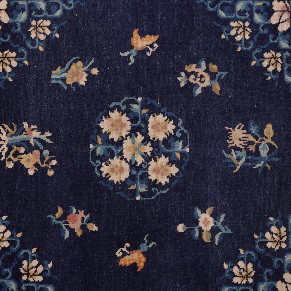 Chinese square blue Peking Floral rug, hand knotted wool pile on a cotton foundation carpet depicting a five blossom floral medallion on centre, surrounded by six varied flowering plants, two butterflies and four corner floral designs, all on a dark