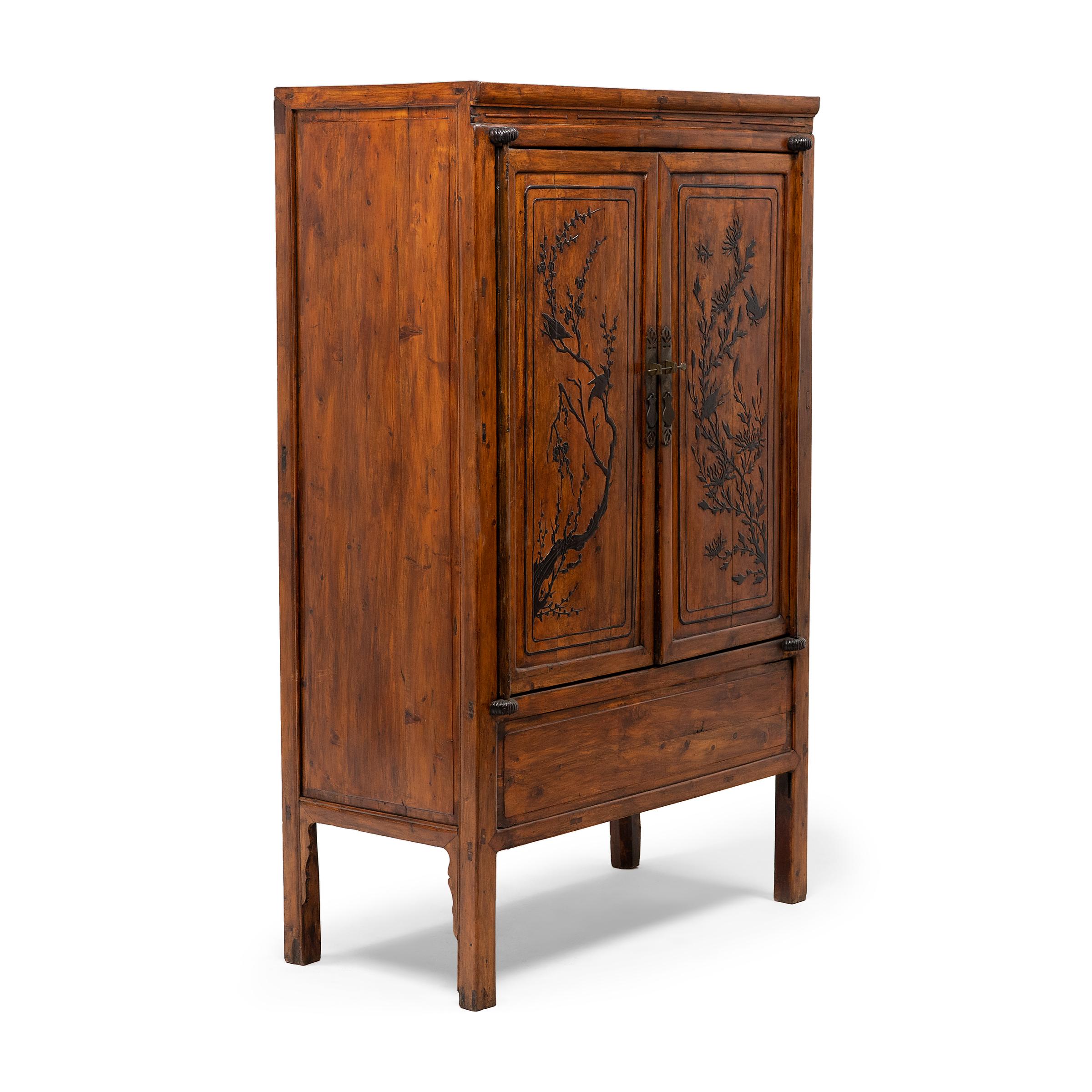 This tall square-corner cabinet from the early 20th century has a simple silhouette and charming low-relief decoration of a traditional bird-and-flower design. Crafted of fir with mortise-and-tenon joinery, the cabinet has a clean-lined form
