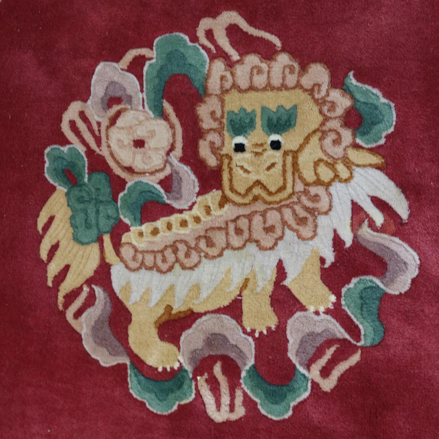 Chinese Nichols School rug features square form with hand-knotted design including central Foo Dog, various floral and urn on rust ground, border with scroll, foliate and floral design, enverso original label; colors include rust red, ivory white,