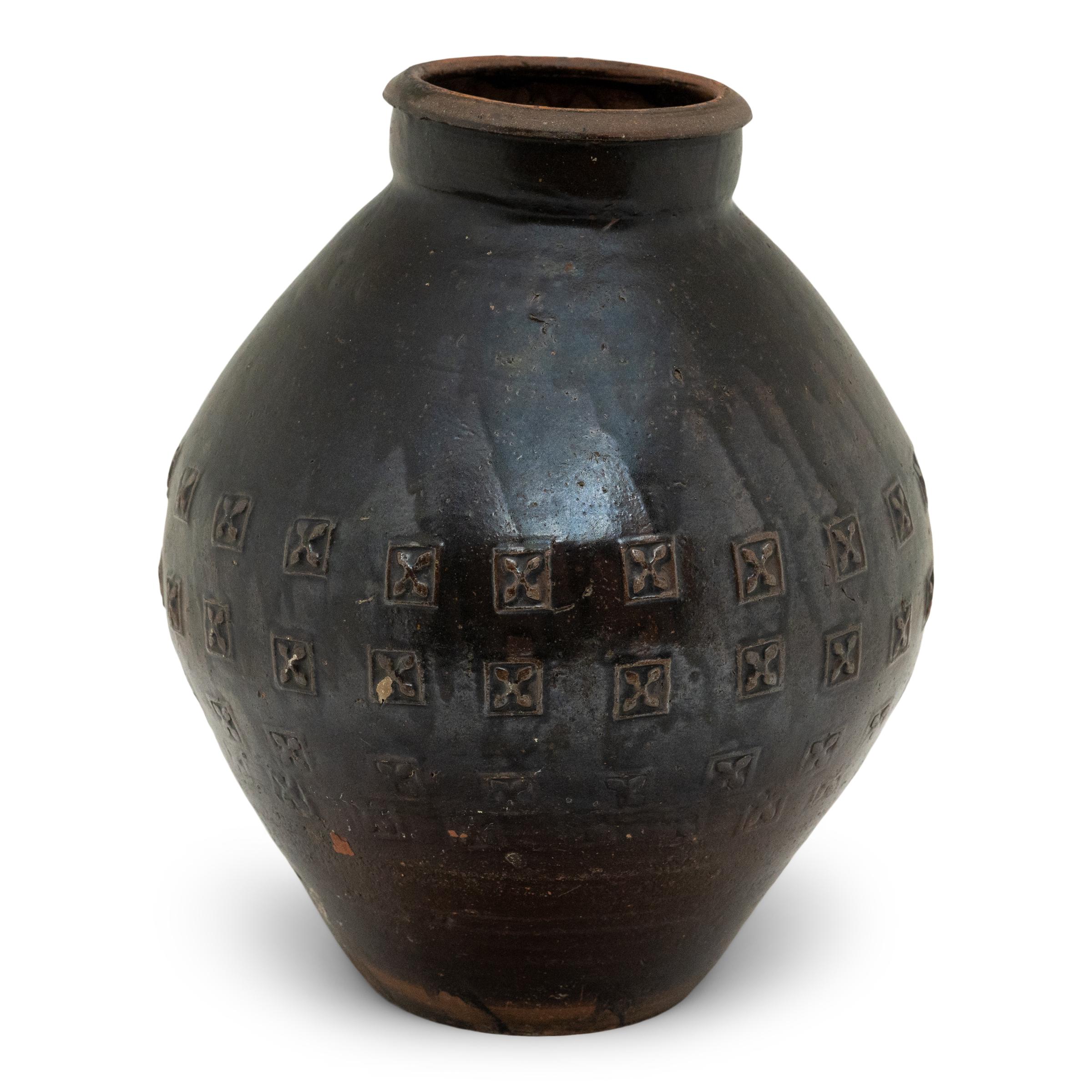 This earthenware vessel from China's Yunnan province is distinguished by its rustic drip glaze and allover stamped pattern. Originally used for storing rice wine or other liquids, the vase has a dramatically tapered form, with bulbous shoulders that