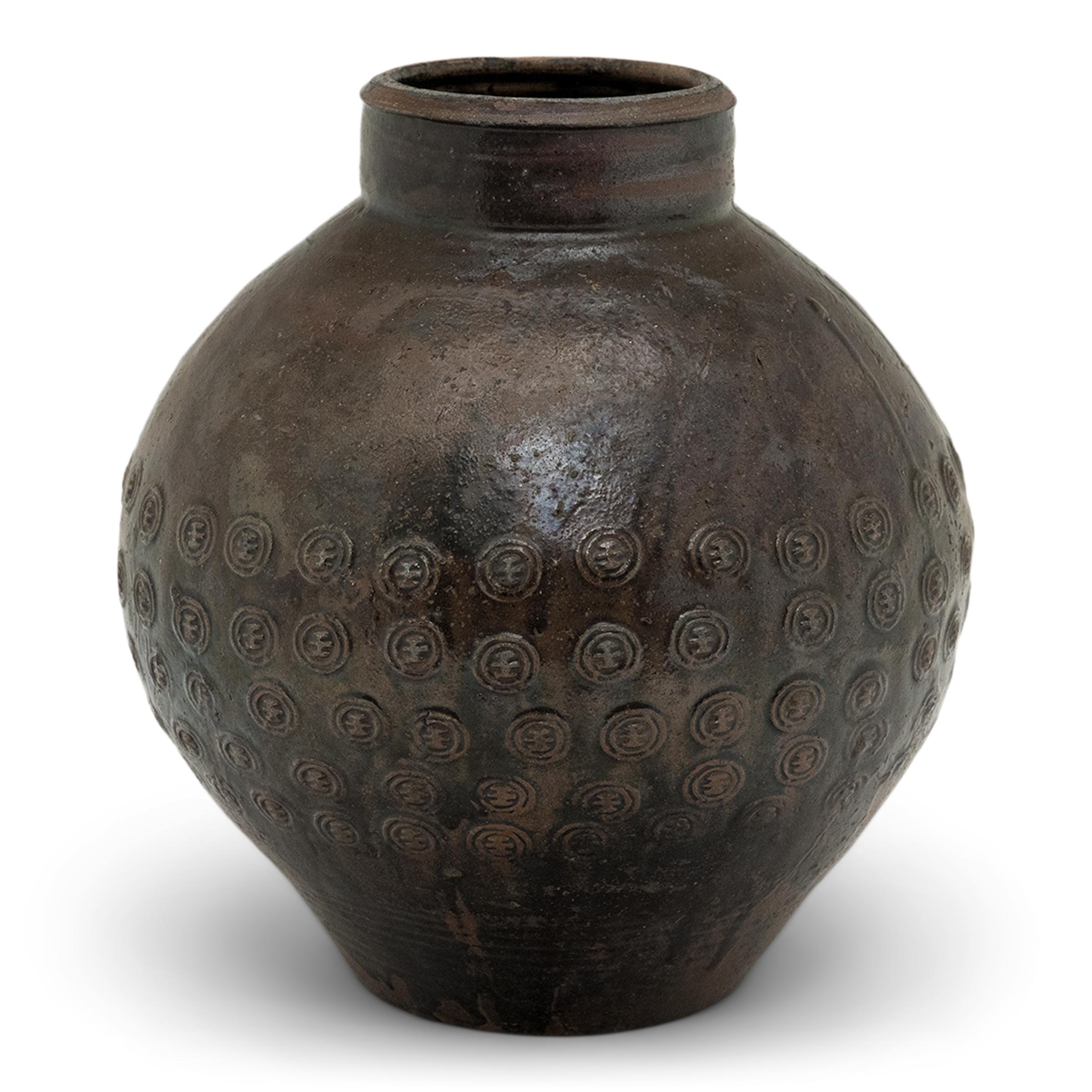 Questo vaso di terracotta proveniente dalla provincia cinese dello Yunnan si distingue per lo smalto rustico a goccia e per il motivo stampato su tutta la superficie. Originariamente utilizzato per conservare il vino di riso o altri liquidi, il vaso