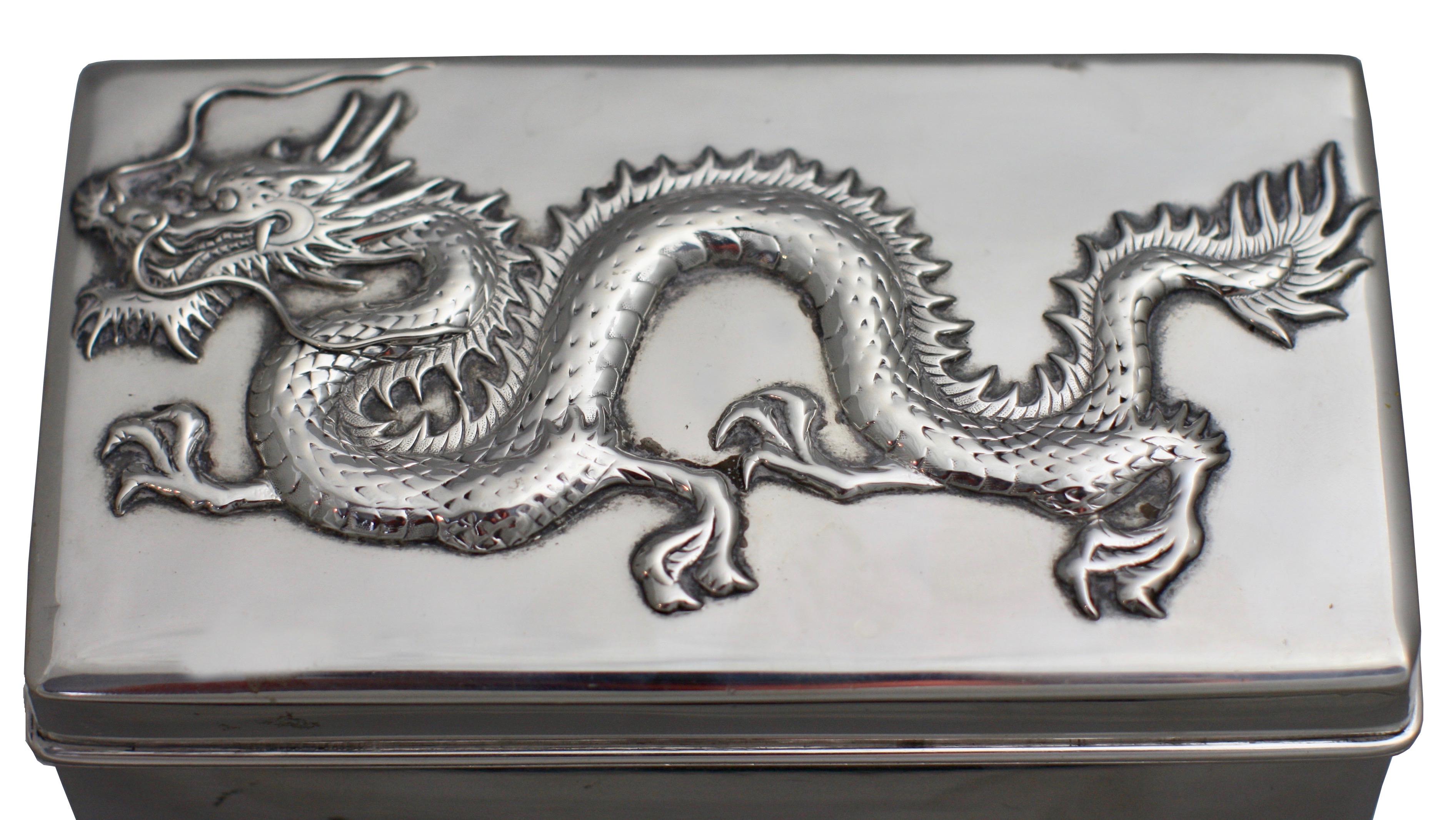 Chinese sterling silver box and cover,
circa 1900, hallmarked and Stamped WH90,
of rectangular form, the hinged cover decorated with an applied dragon, wood lined.
Measures: Length 6 in. (15.24 cm.)
Width 6 1/2 in. (16.51 cm.)
Depth 3 1/2 in.