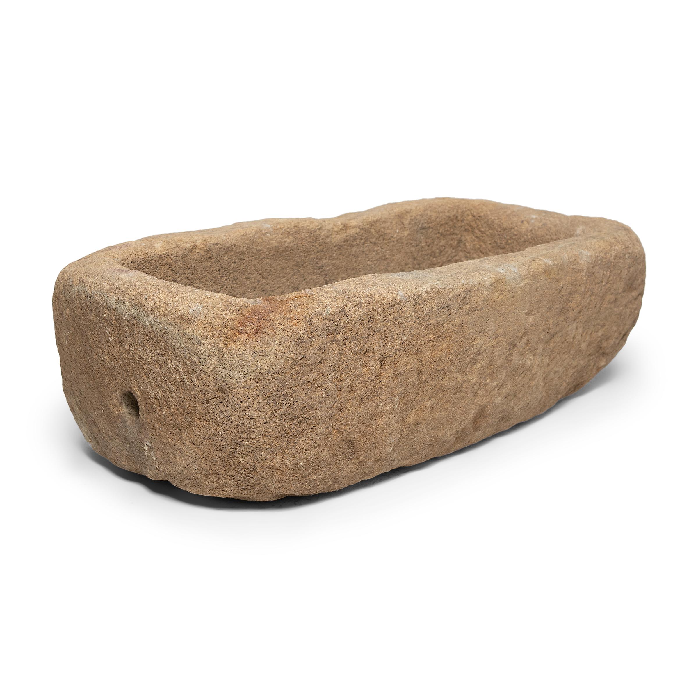 Once used on a provincial Chinese farm to hold water or animal feed, this early 20th-century stone trough is celebrated today for its organic form and rustic authenticity. Hand-carved from solid limestone, the trough has a shallow, rectangular form