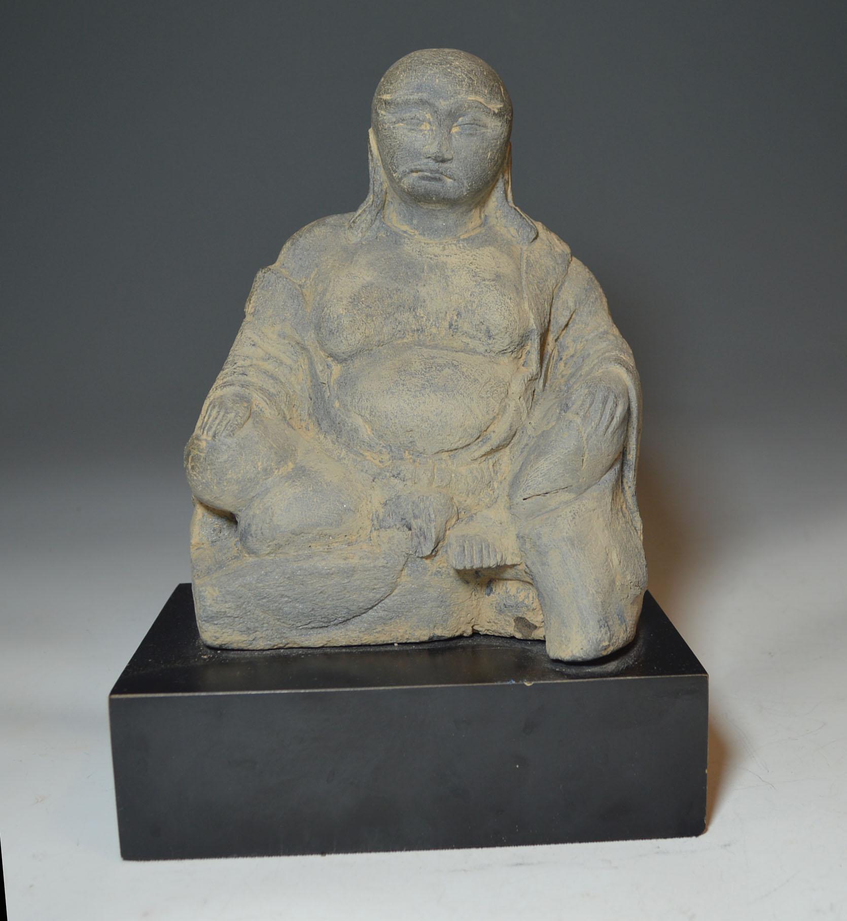 A antique Chinese stone figure of a seated Lohan 

A portly figure of a lohan with mustache and long ear lobes seated in a relaxed posture with open 
robe.

China, Ming dynasty, 15th-16th century or earlier.

Green limestone size 8 1/4 x 6 inches.