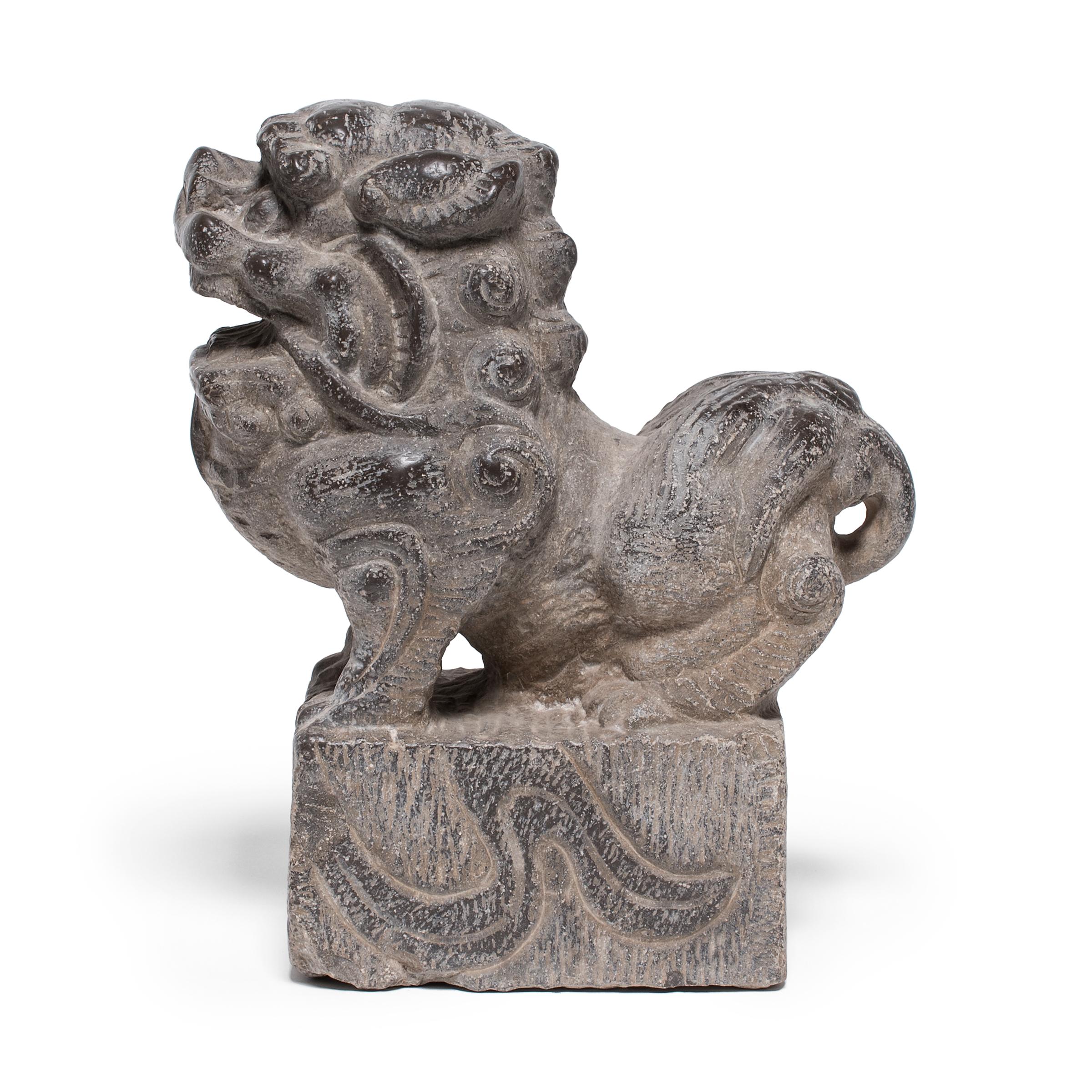 Hand-carved from a single block of limestone, this stone fu dog sits at attention as a watchful guardian of the home. He exudes a remarkable sense of life and energy - crouched on all fours with curly hair and a lively expression. Also known as