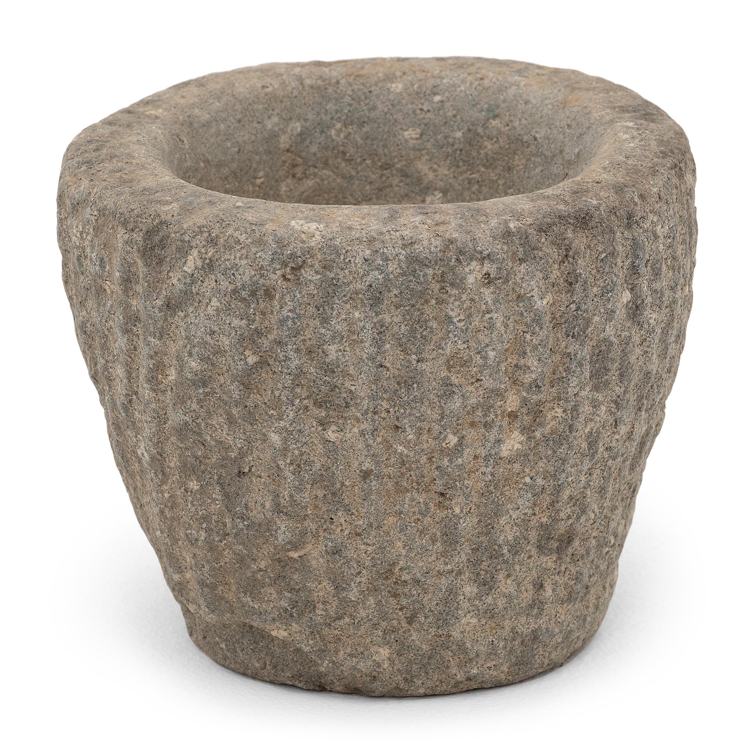 Ricavato da un unico blocco di granito, questo recipiente in pietra è un mortaio dell'inizio del XIX secolo utilizzato in una cucina cinese per macinare spezie, erbe e altri condimenti. I segni dello scalpello caratterizzano l'esterno della pietra