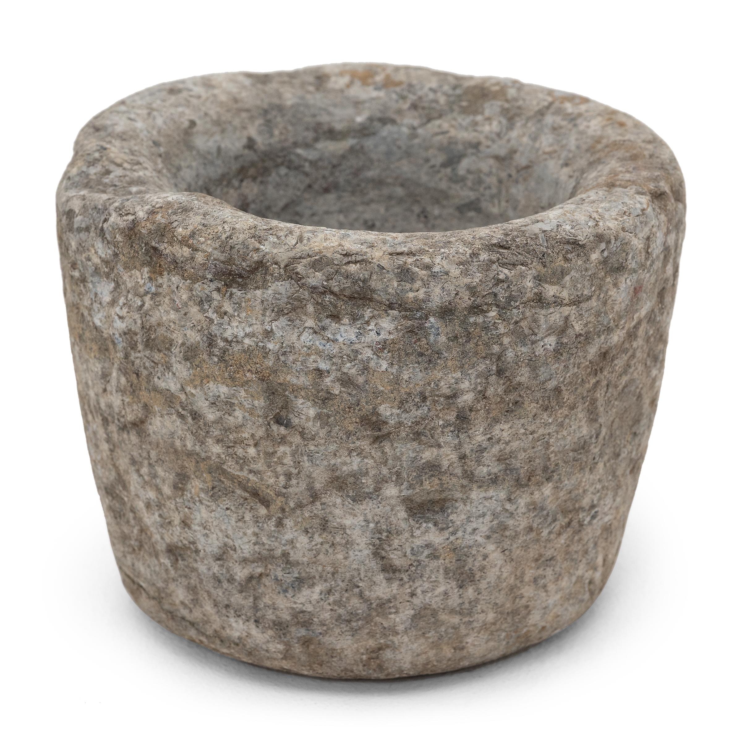 Carved from a single block of granite, this stone vessel is an early 19th century mortar once used in a Chinese kitchen to grind spices, herbs, and other condiments. The exterior has the organic texture of raw stone, while the interior is smooth to