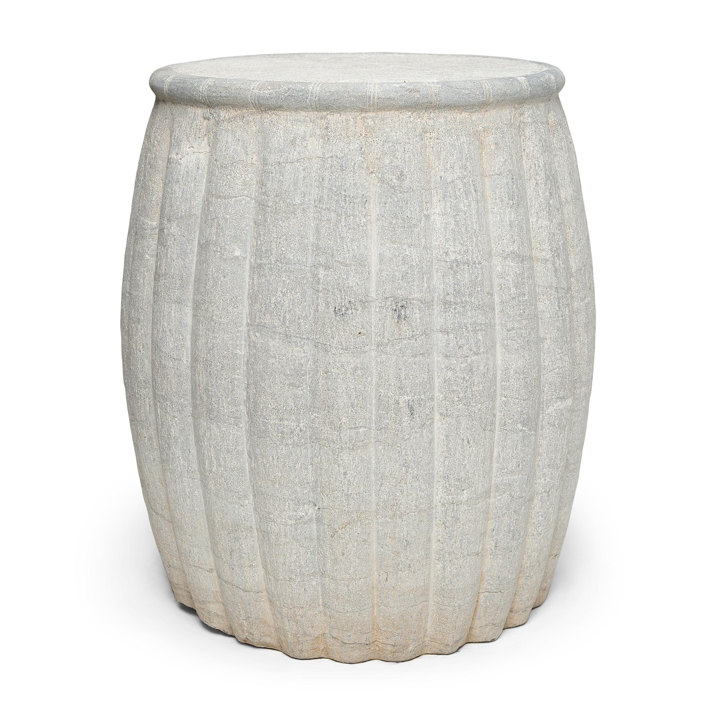 This large stone drum stool was carved from solid limestone with a ribbed texture suggestive of a squash or melon, traditional symbols of longevity and perpetuity. The drum-form stool swells with gently tapered sides and a flattened top bordered by