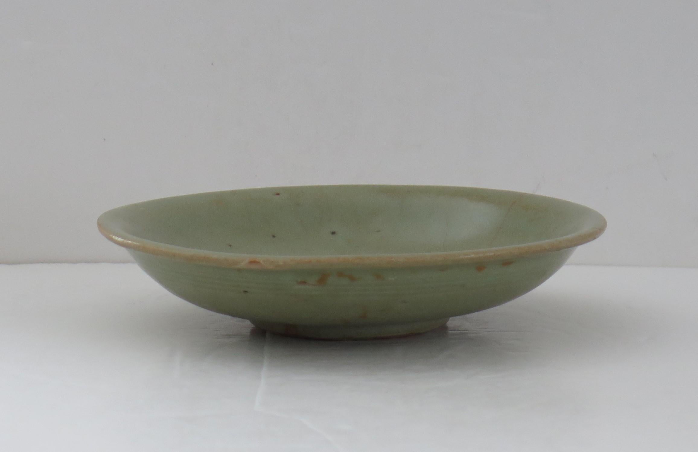 This is a very old interesting Chinese stoneware Longquan Celadon bowl or plate with incised decoration, which we date to the Yuan Dynasty, circa 1300.

The bowl is well potted on a low foot. 

The bowl is an olive green colour having a celadon