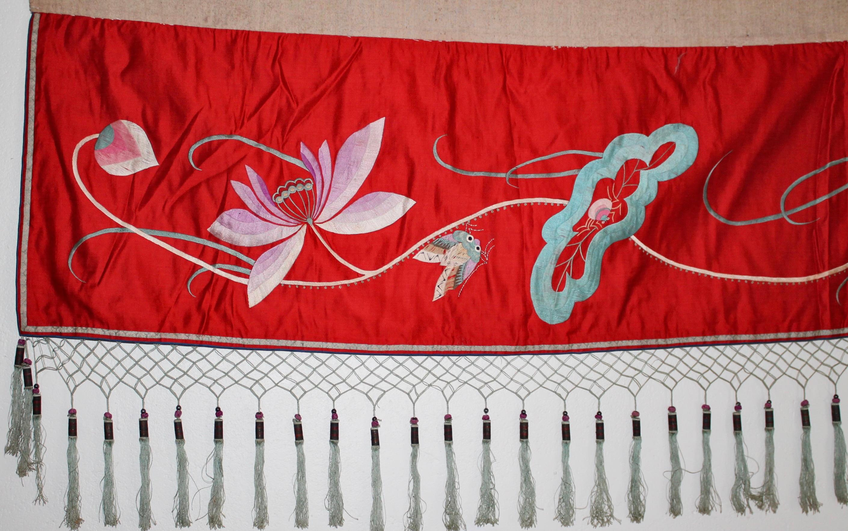 Una seda china del Estrecho finamente bordada a mano con motivos de estilo decó; grulla, plantas e insectos. Sobre un rico campo de seda roja.
Borlas de seda con pesas de madera suspendidas de la red en el borde inferior de la cenefa.