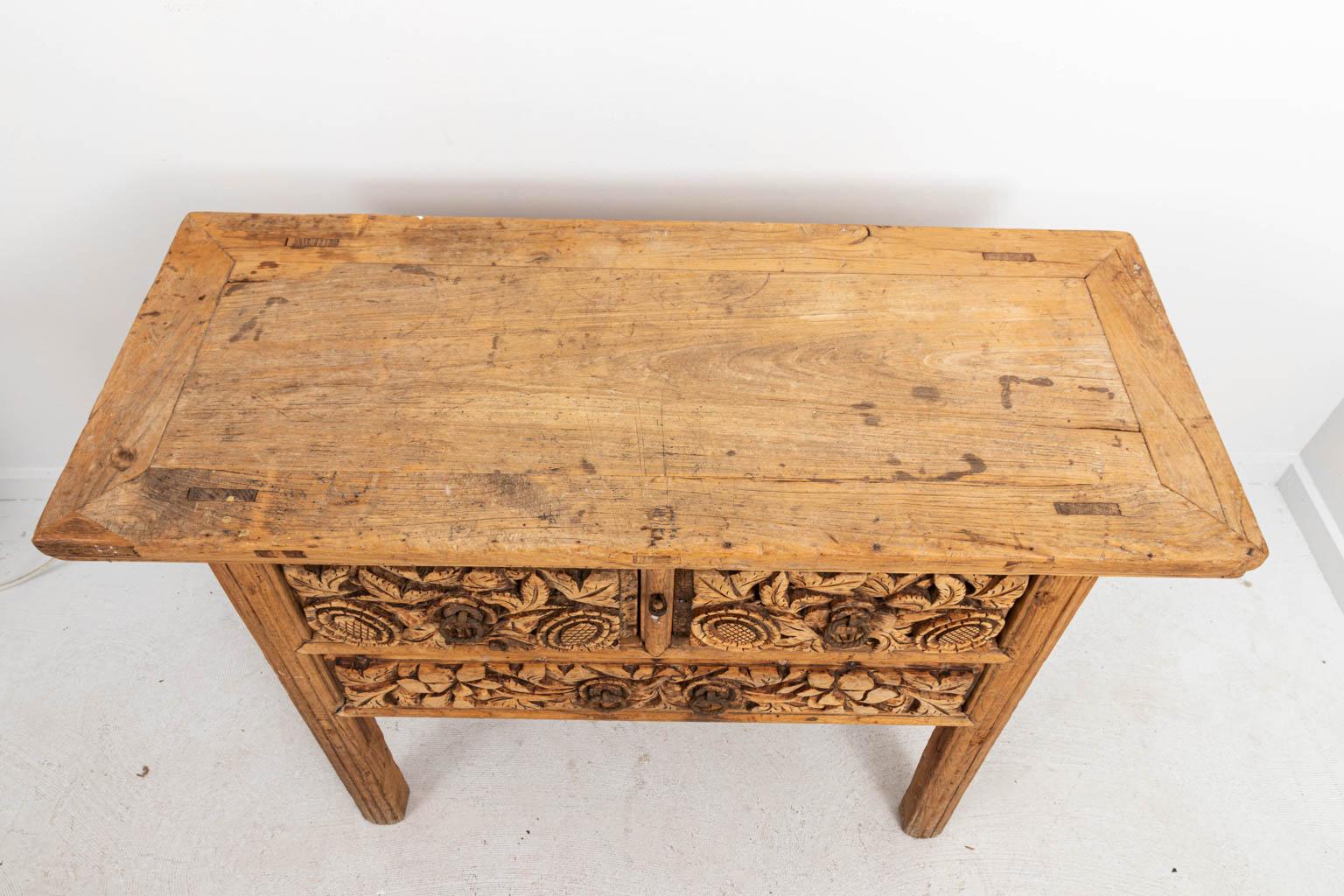 Chinese stripped wood console table with two carved drawers and square legs, circa 19th century. The piece also features heavy relief details of foliage on the drawer fronts and iron hardware. Please note of wear consistent with age including
