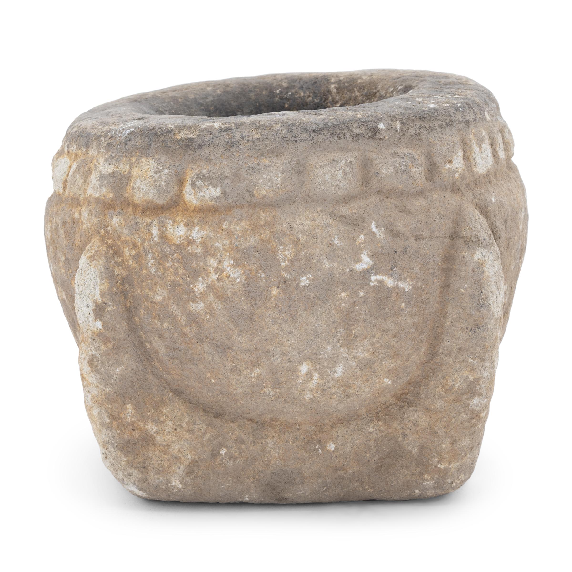 This stone mortar from the early 20th century was once used in a provincial kitchen to grind herbs, spices, rice, and other foods. Hand-carved from a solid block of limestone, the mortar has a rounded body with a square base and a flattened rim. A