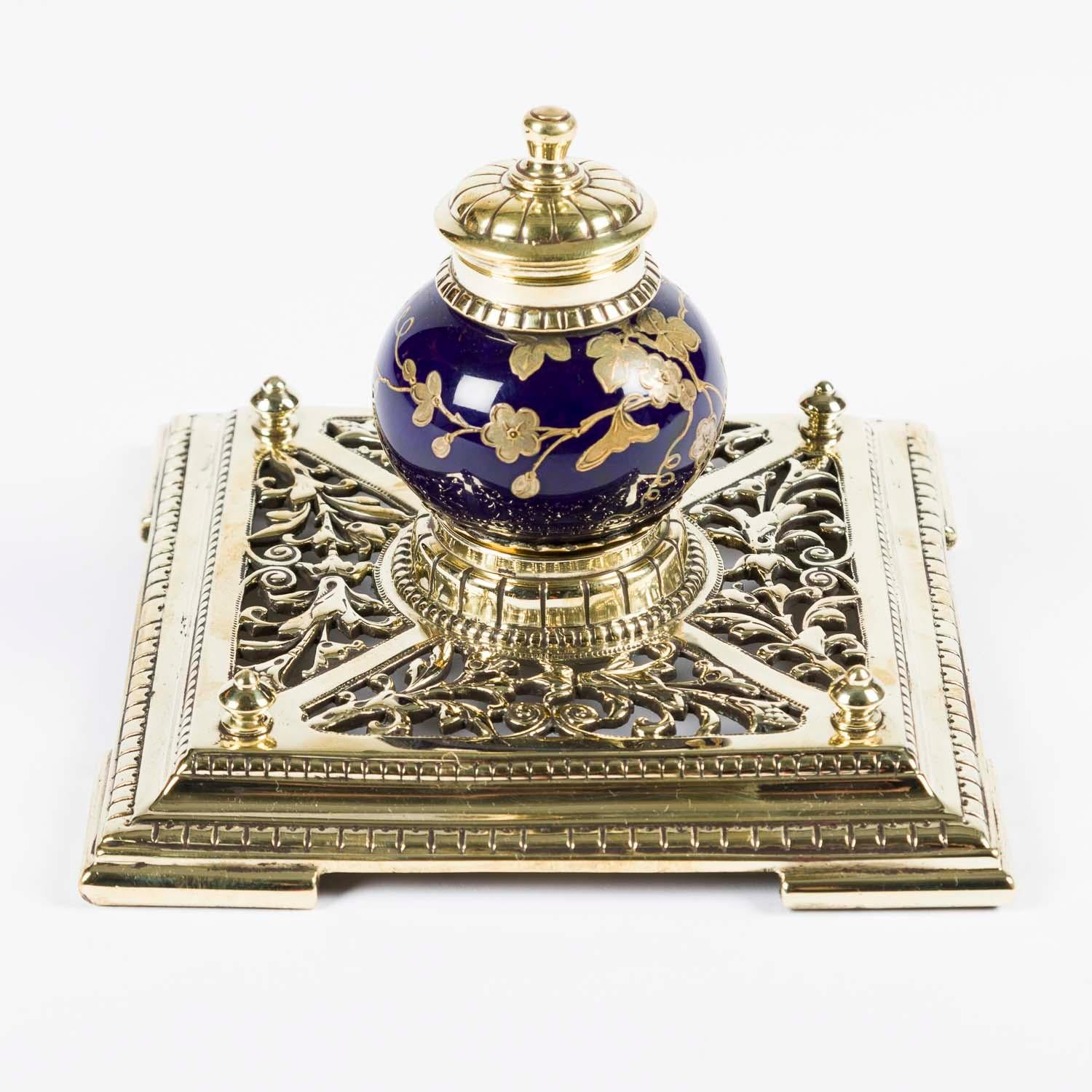 A Chinese style blue and gold ceramic inkwell, with a hinged brass lid, mounted on a reticulated brass base.