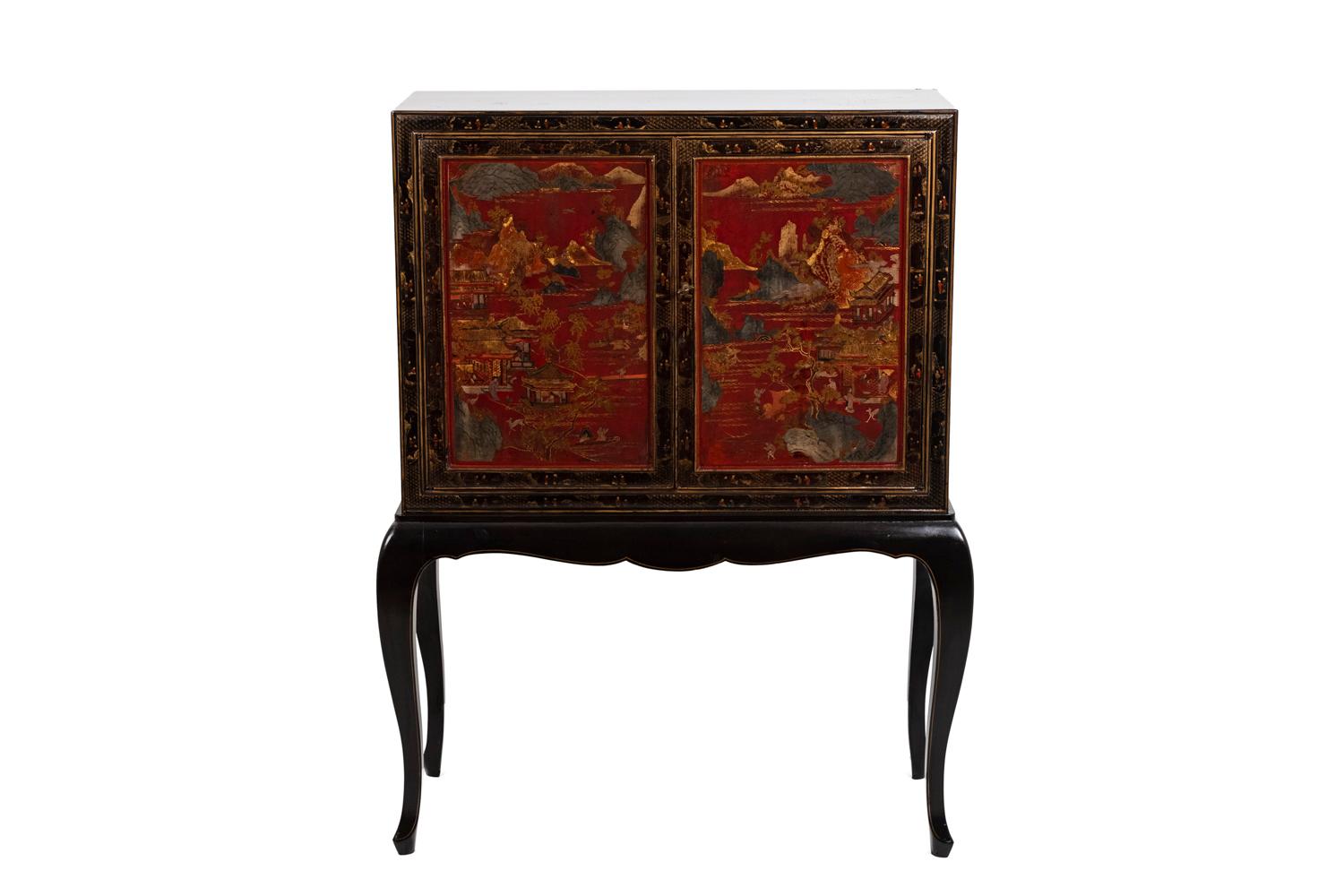 Chinese style cabinet in black and red lacquered wood with gilt highlights opening by two-door leaves on a compartment with a shelf. It stands on four cabriole legs. Decor of two cartouches on the door leaves framing Chinese style landscape scenes
