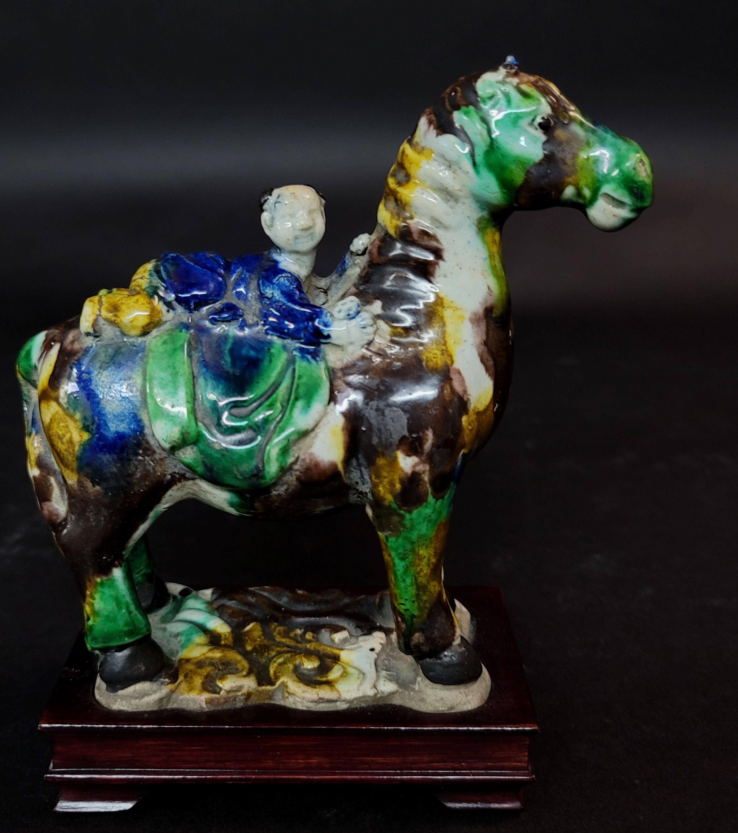 Figure chinoise en glaçure Su Sanci représentant un cheval et un garçon. La décoration de Sancai utilise des glaçures principalement de trois couleurs : brun ou ambre, vert ou blanc crème, avec l'utilisation plus rare du bleu. Bien qu'elle soit