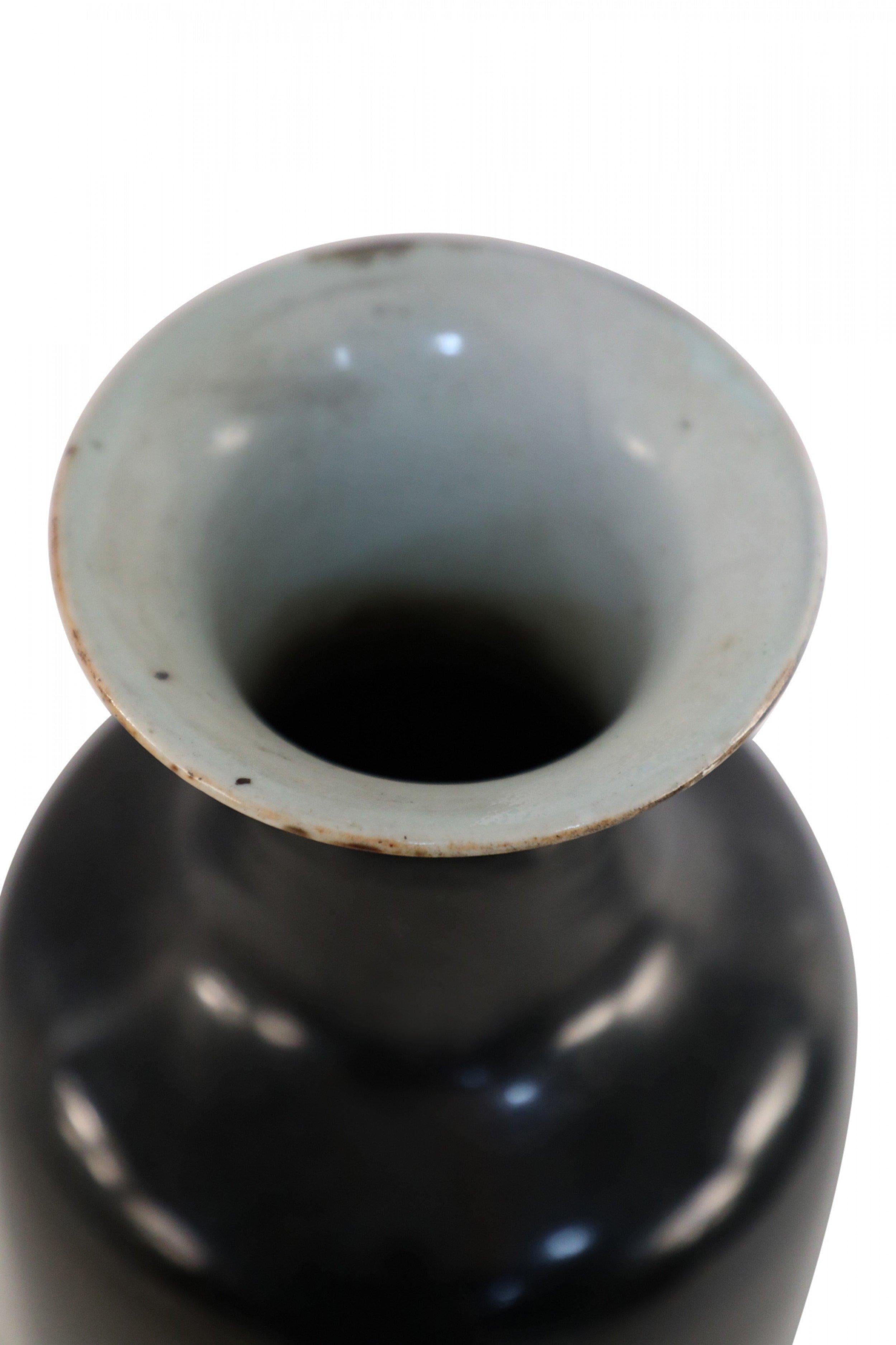 Chinese black glazed porcelain vase with a tall, slim shape and a white interior.
  