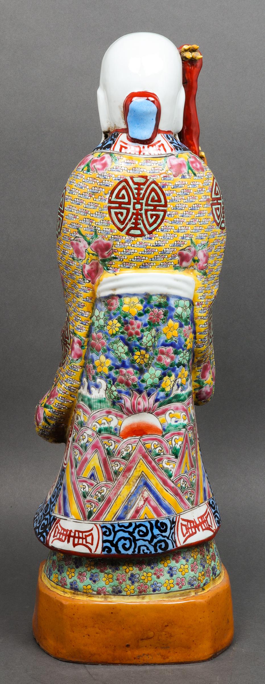 Chinese polychrome glazed ceramic figural sculpture of Shou-Lao, god of longevity, holding a dragon staff in one hand and a peach in the other, his elaborate robe with shou symbols, peaches, and floral design, stamped to underside. 21