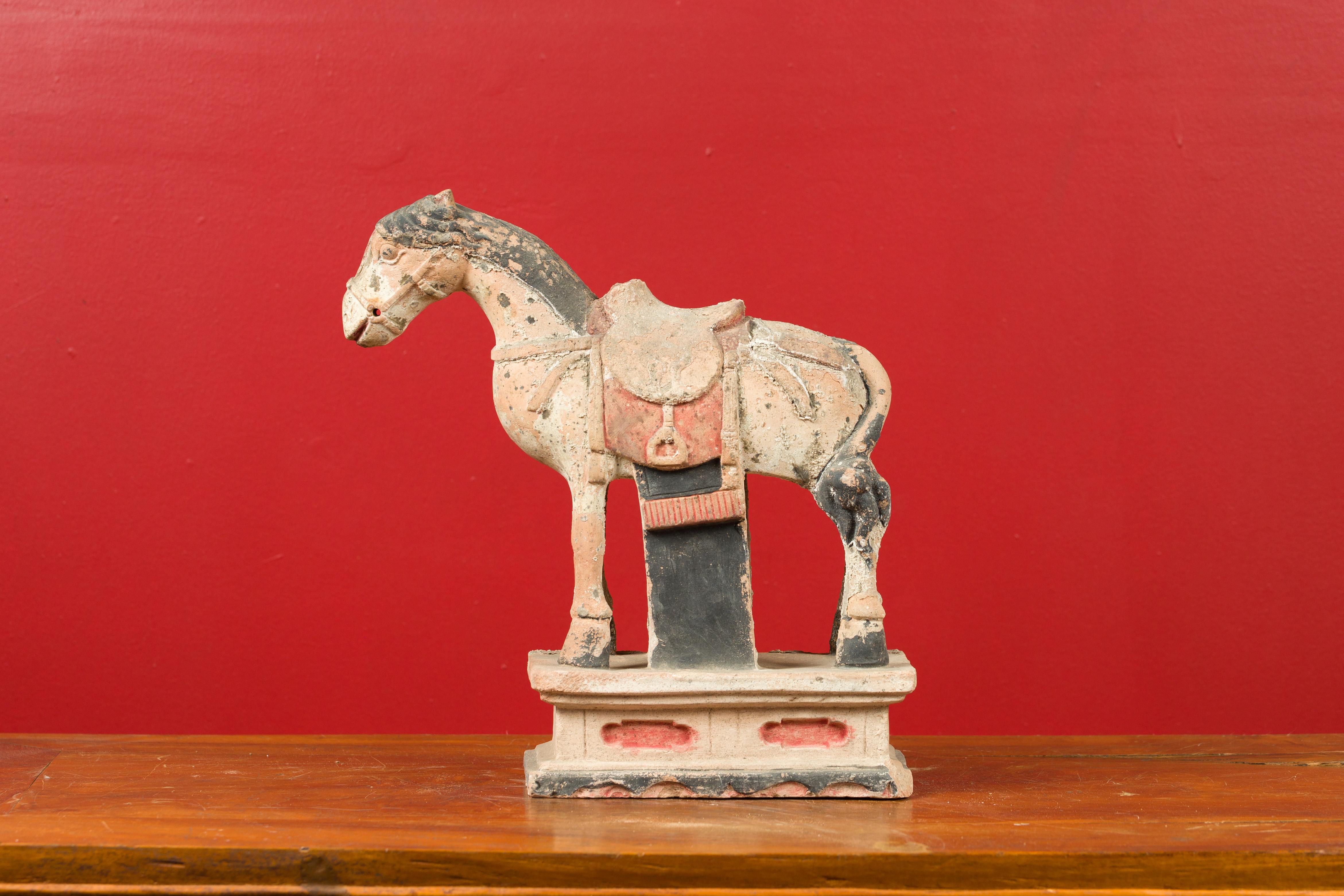 A small Chinese painted Ming Dynasty horse sculpture with original pigmentation. Charming us with its joyous expression and its original finish, this petite painted Ming Dynasty figurine depicts a horse standing foursquare on a pedestal carved with