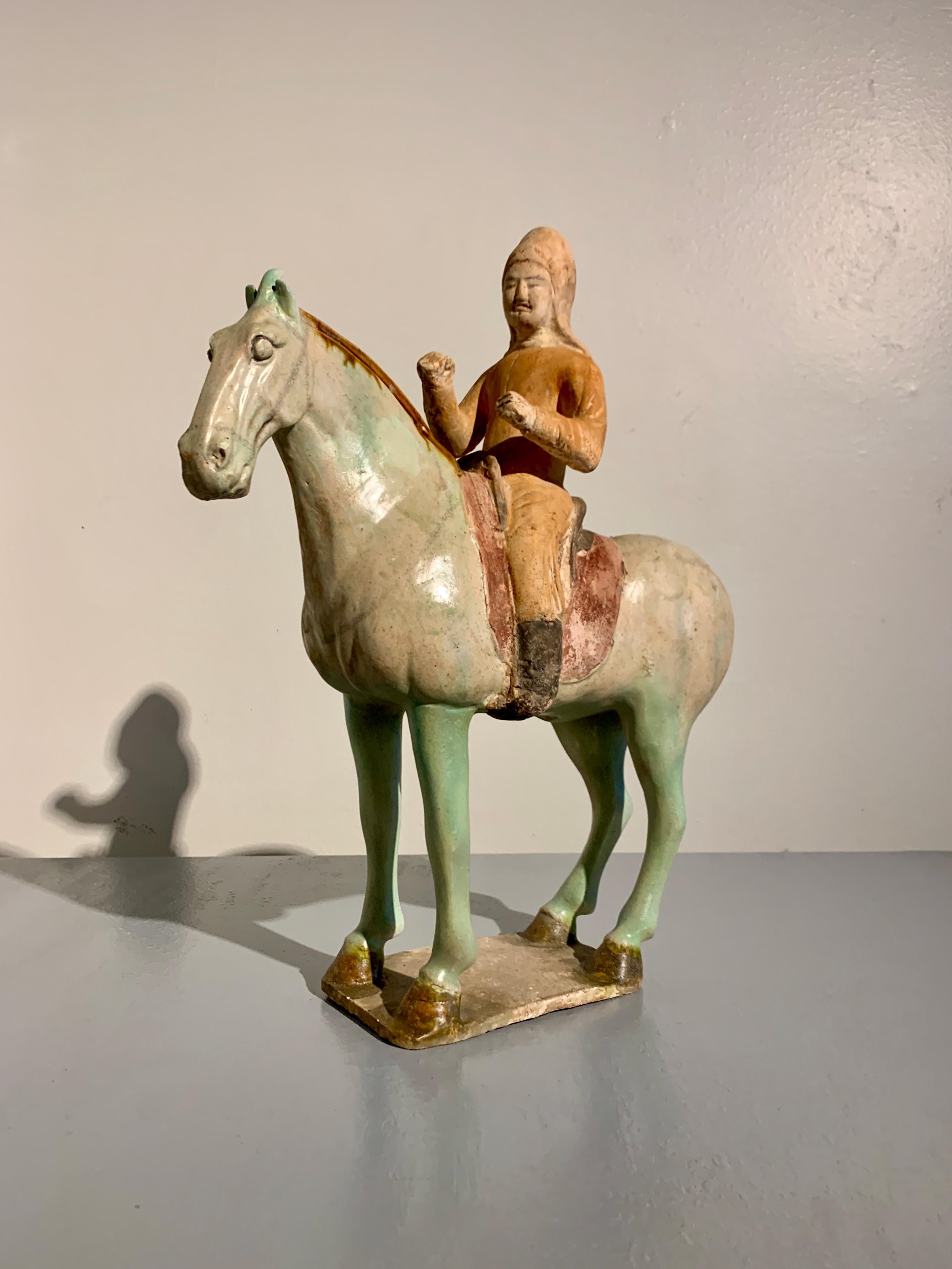 A fine and unusual Chinese Tang Sancai glazed model of a horse and rider, Tang Dynasty (618 to 906 CE), early 8th century, China.

This fantastic sculpture portrays a male figures seated in a saddle upon the back of a noble horse. 

The figure is a