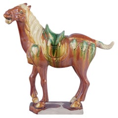 Caballo chino estilo Tang Dynasty en cerámica. Esmaltado en tonos marrones y verdes.