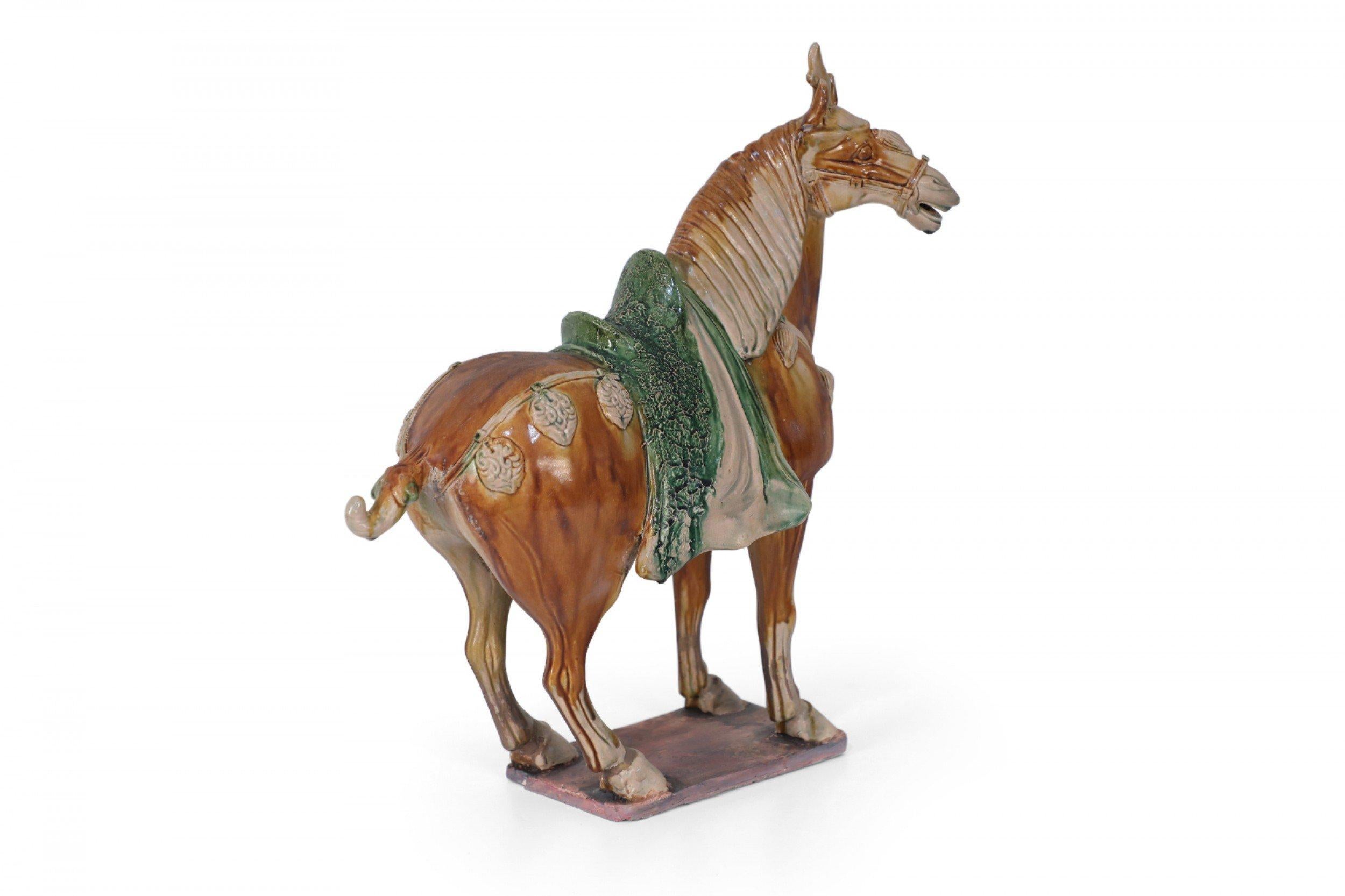 Antique Chinese Tang Dynasty-style terra cotta figure of a horse commonly used as a tomb figure for wealthy burials in the 7-8th centuries, and crafted with traditional tri-color glaze, or Sancai, utilizing brown, green and off-white.
 