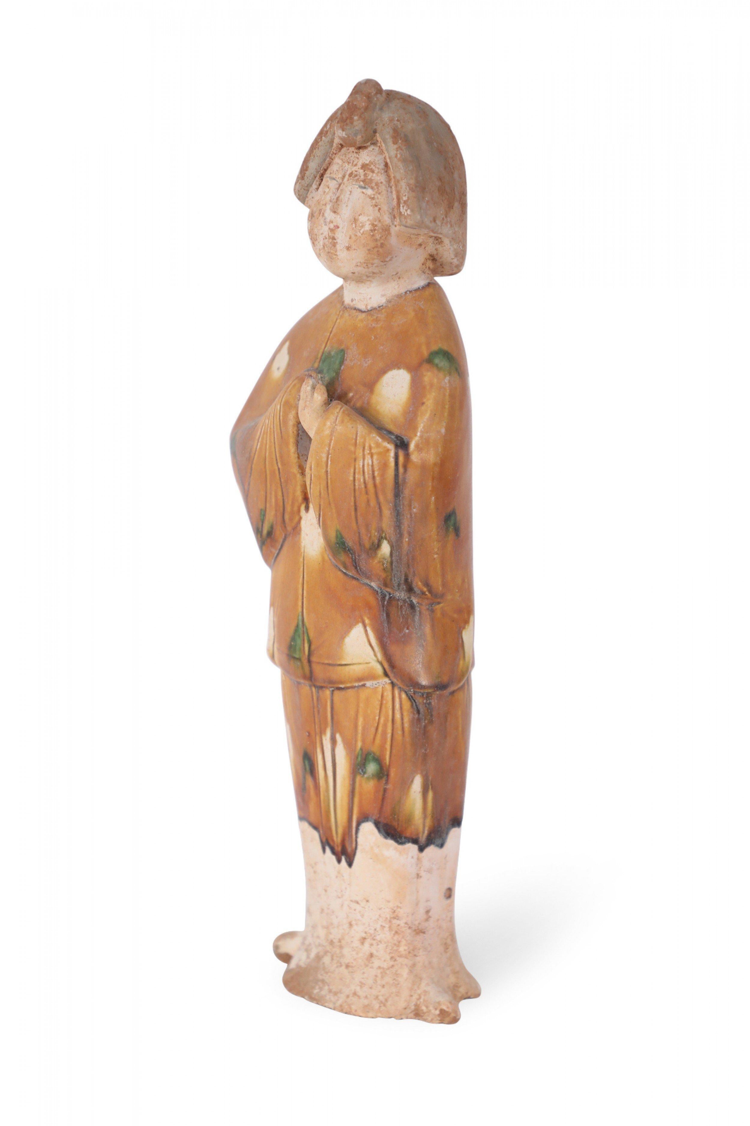 Antica figura in terracotta cinese della dinastia Tang di una donna che indossa abiti con la tradizionale smaltatura tricolore della dinastia Tang, o Sancai, che utilizza il marrone, il verde e il bianco sporco.
  