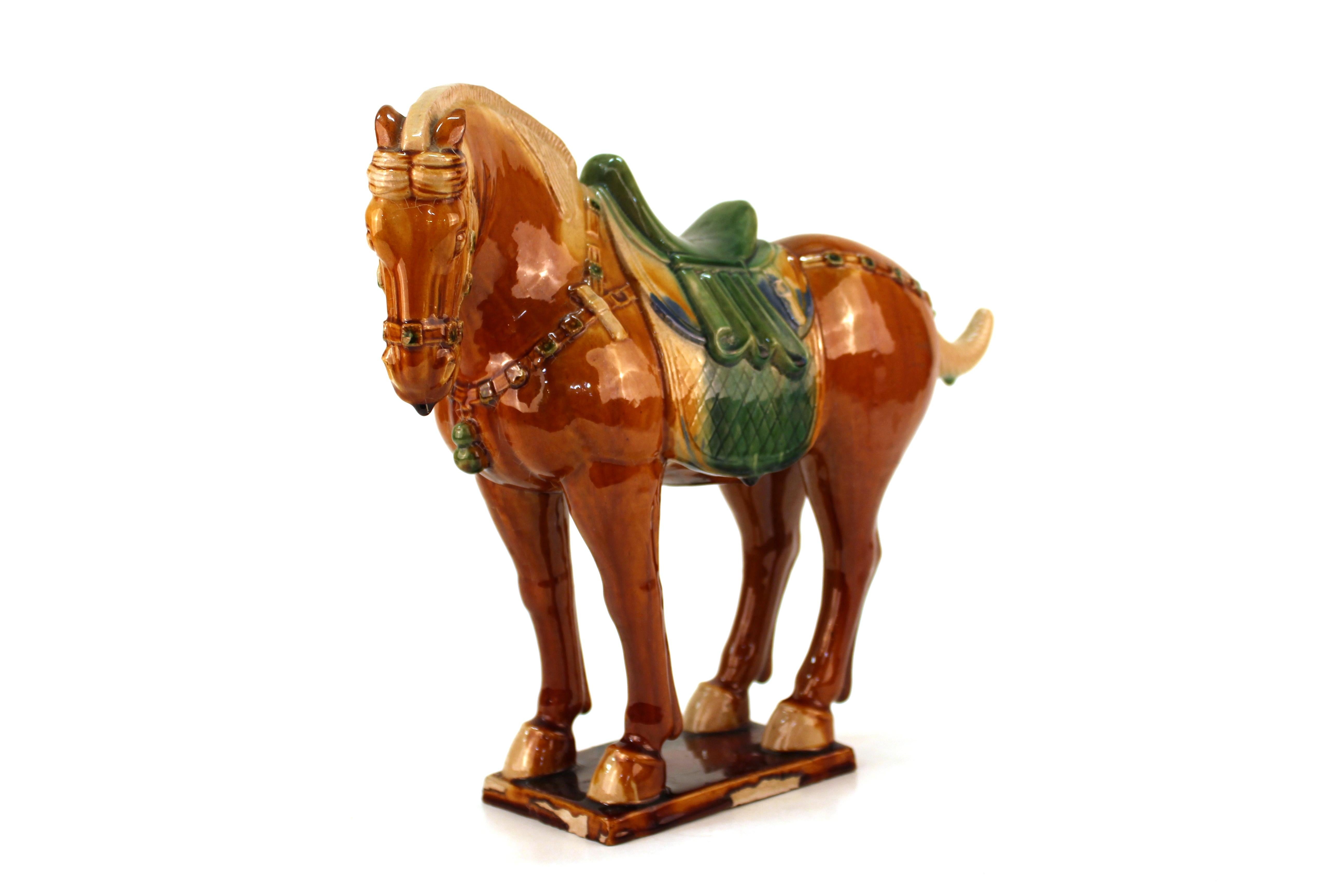 Chinese Tang manner Sancai-glazed pottery statue of a horse standing on all four legs atop a rectangular base, its head slightly turned to the side. Glaze drips to tip of nose and lower lip and tail. Slight firing imperfection to the mane.