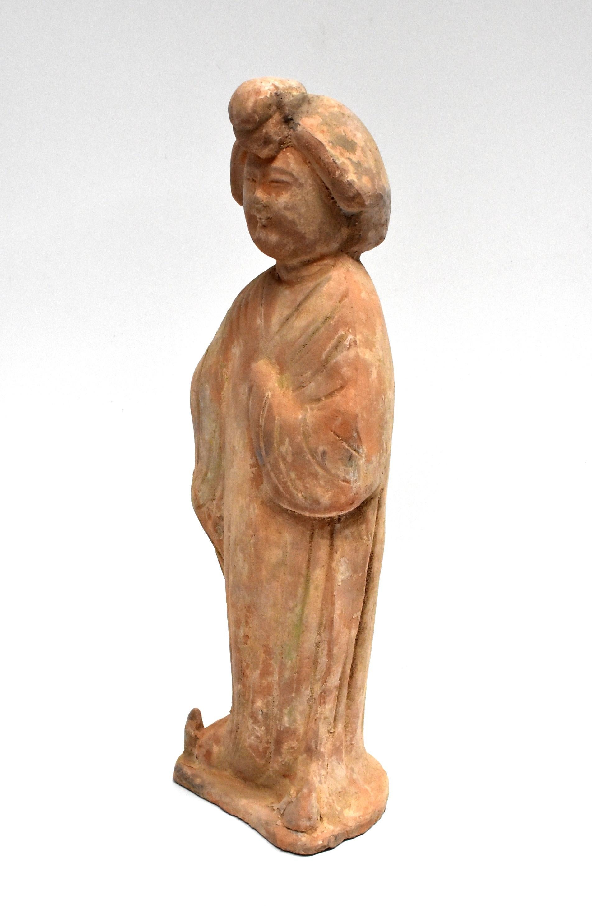 A great example of Chinese Tang dynasty pottery figure. The figure is a court lady, with a full face and traditional hair style. She stand with one hand in front and the other behind. Her face tilts up slightly and is smiling.