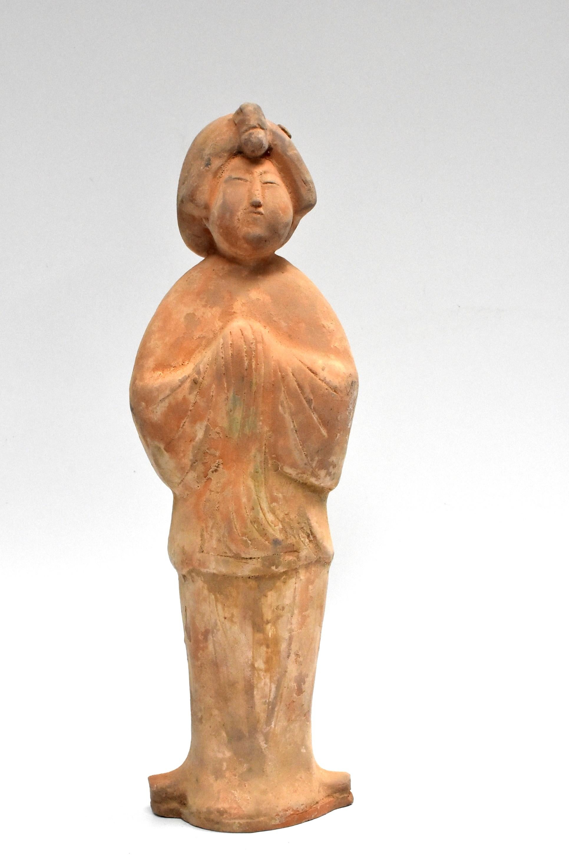 A great example of Chinese Tang dynasty pottery figure. The figure is a court lady, with a full face and traditional hair style. She stand with both hands in front. Her face tilts up slightly and has an empathetic expression.