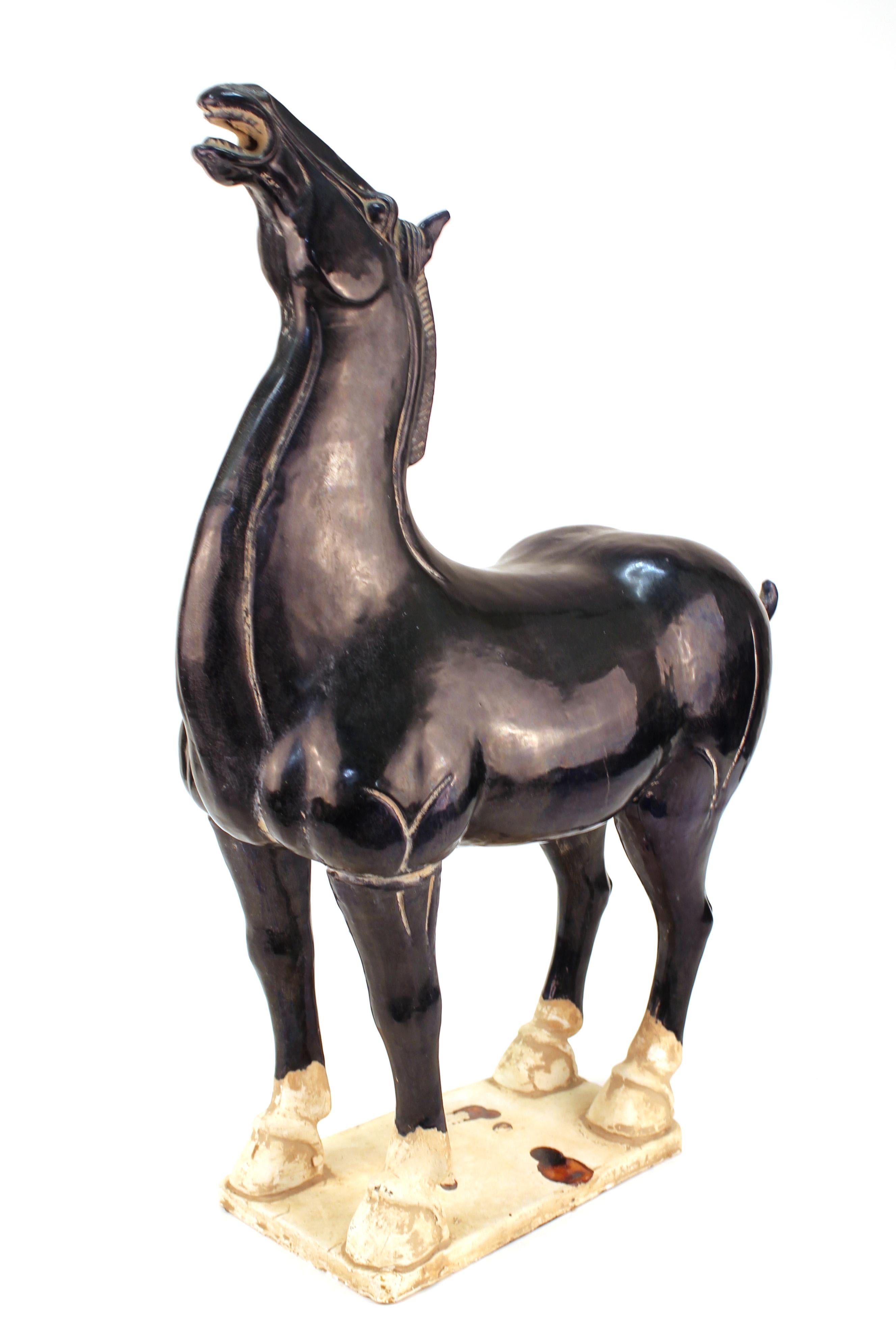 Chinese terracotta sculpture of a horse inspired by the Tang dynasty. The horse is glazed in a dark blue color and has drippings on its base. Part of drippings disappeared from the base. The piece is in overall great vintage condition.