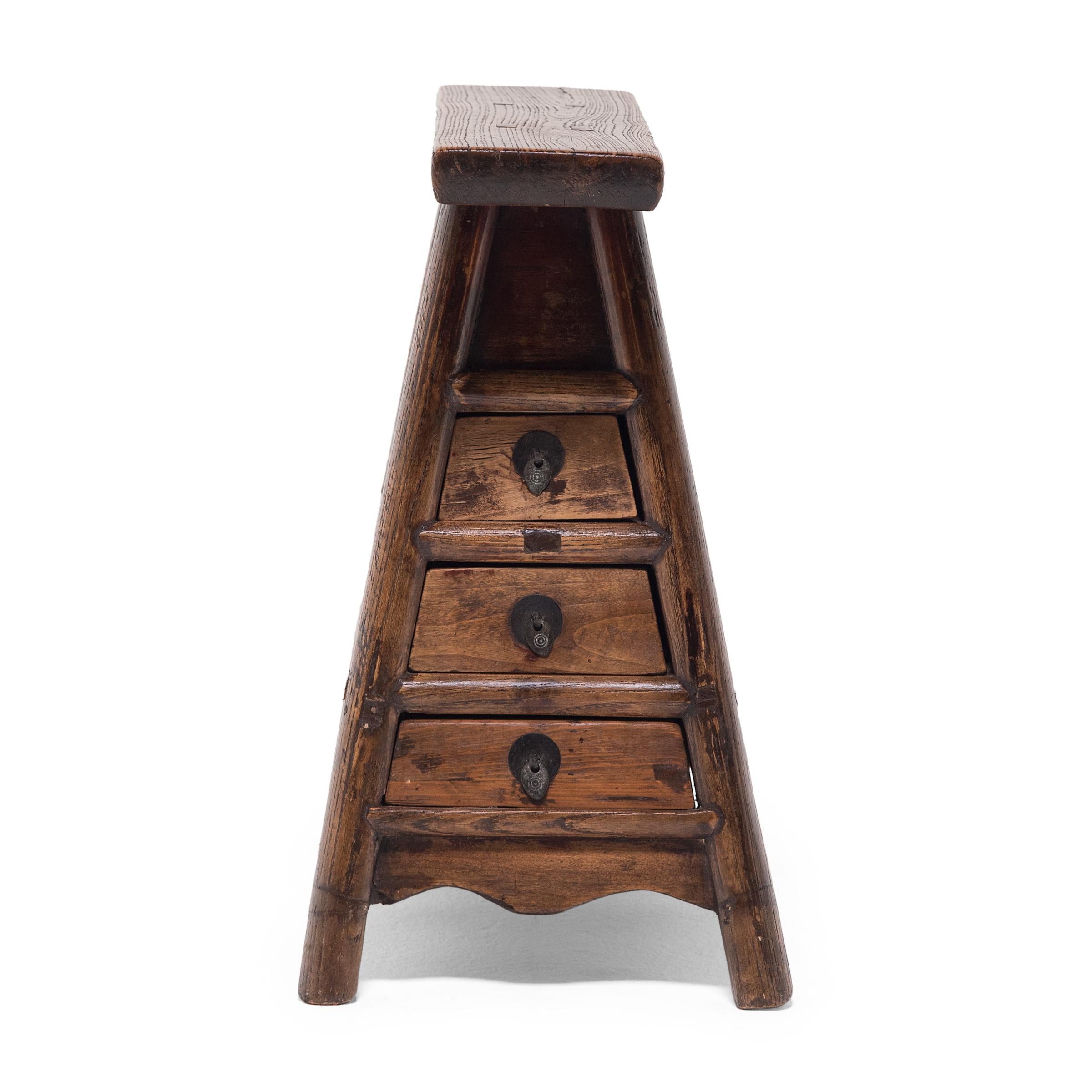 This unusual stool is a 19th-century barber's stool designed to be carried from place to place for roadside haircuts. Crafted with traditional mortise-and-tenon joinery, the stool has a splayed-leg frame with enclosed sides, an elongated seat, and