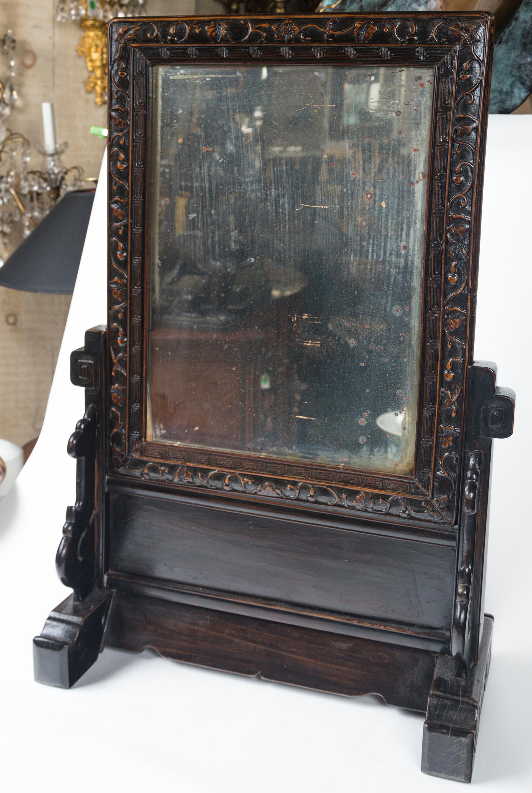 The mirror lifts out of the stand. The mirror alone measures 18.25 tall and 14.75 wide. The dimensions shows are the over all dimensions. Classic, delicate Chinese style hand carving covers almost all of the wood. The distressed glass, seems