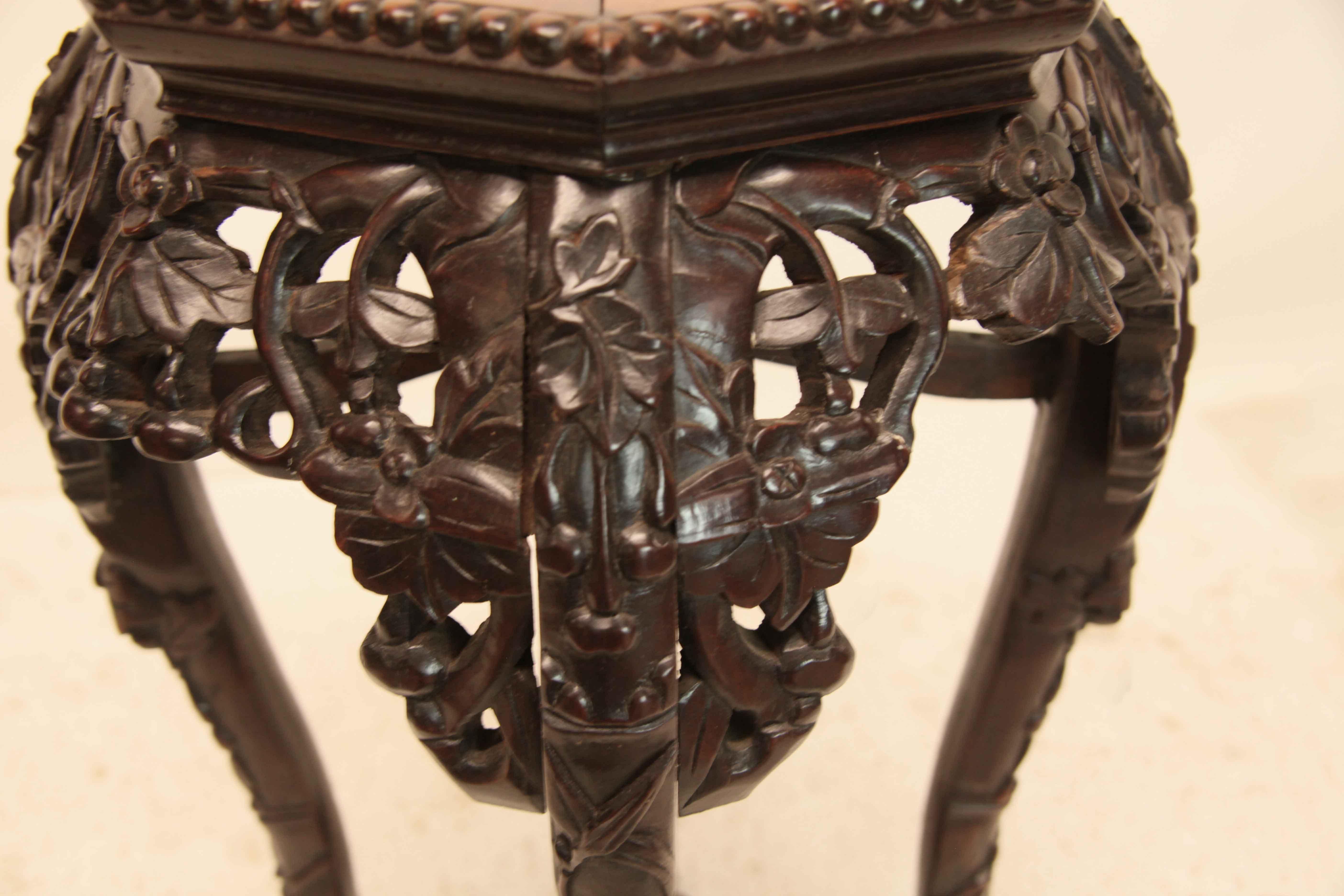 Chinese teak wood stand, the hexagonal top with a beaded edge has a marble inset which is similar to rojo breccia, below is a repeated pattern around the stand of reticulated carving in high relief featuring stylized flowers and foliate; the