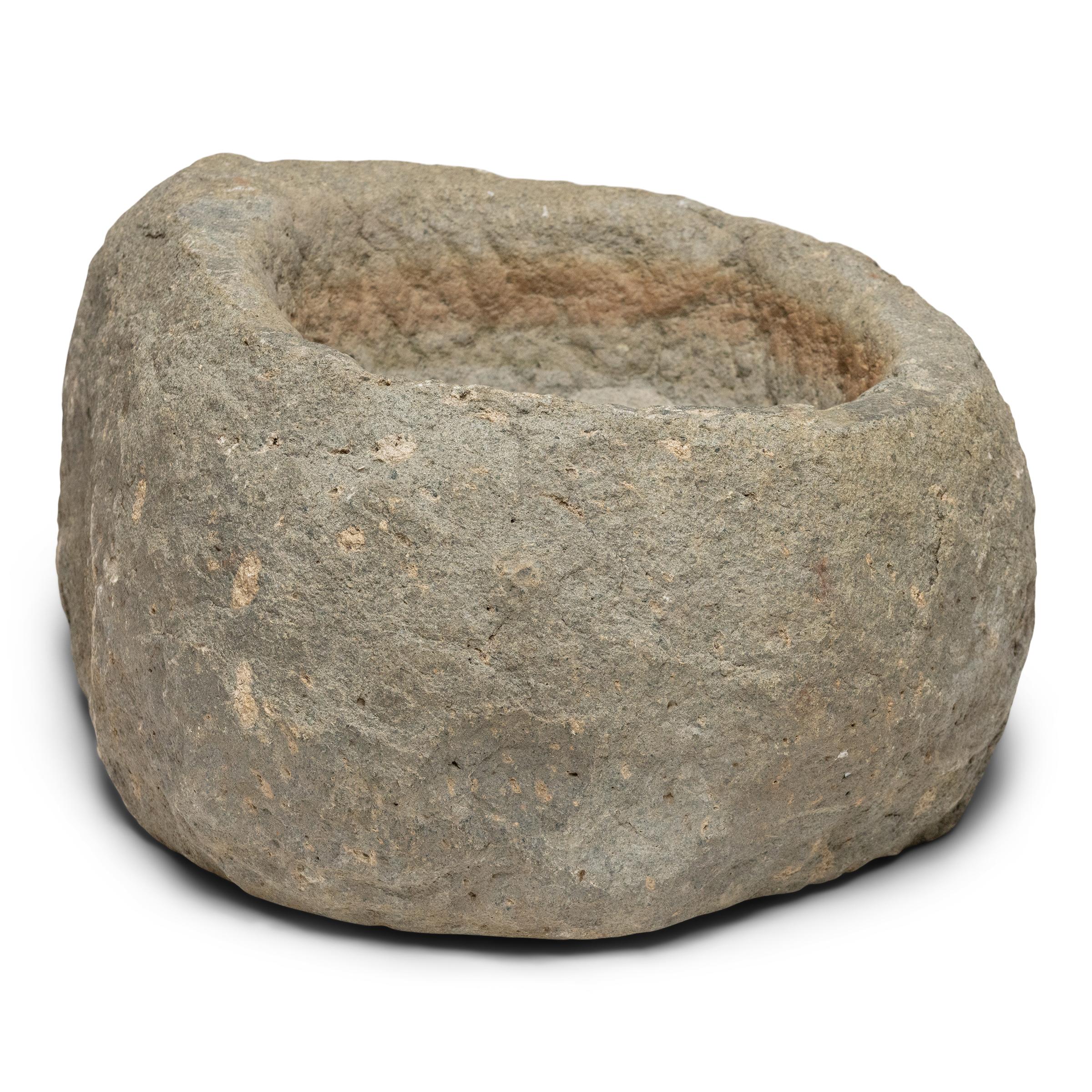 This stone basin was carved by hand nearly two centuries ago, sculpted from solid limestone with irregular texture and an asymmetrical teardrop shape. A pattern of chiseled grooves adds rustic character to the interior and softens towards the base