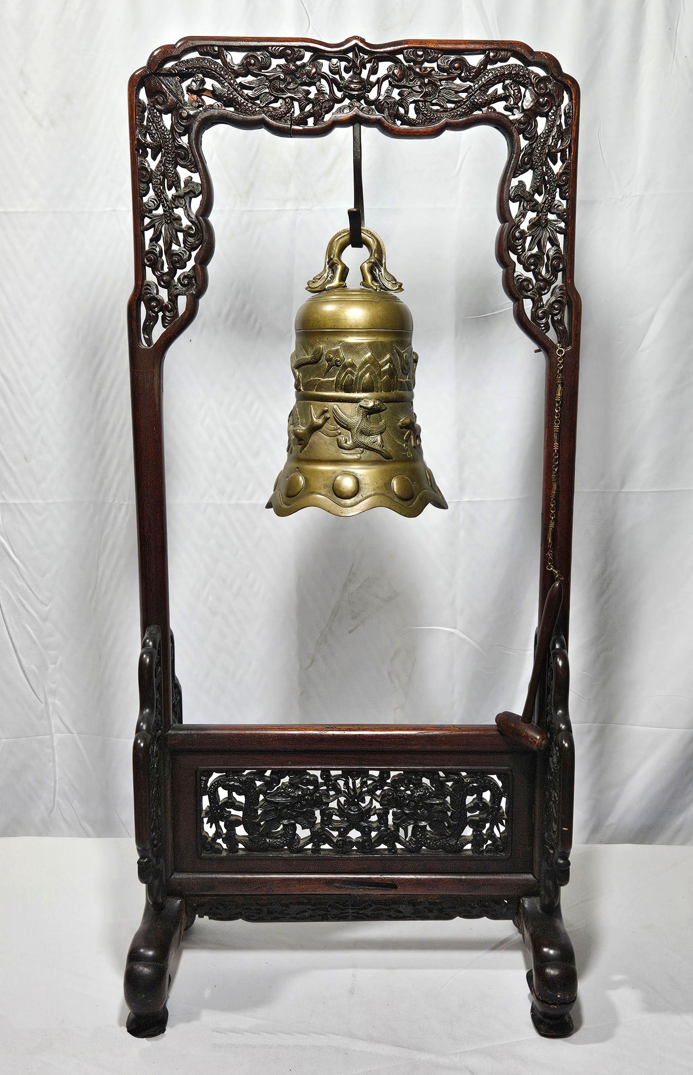 China, Ca. The stand: 18th - early 20th century Bell:
The intricately carved hardwood stand with openwork dragon borders, spandrels and apron with large iron hook suspending a Ming style bell, well cast with relief


