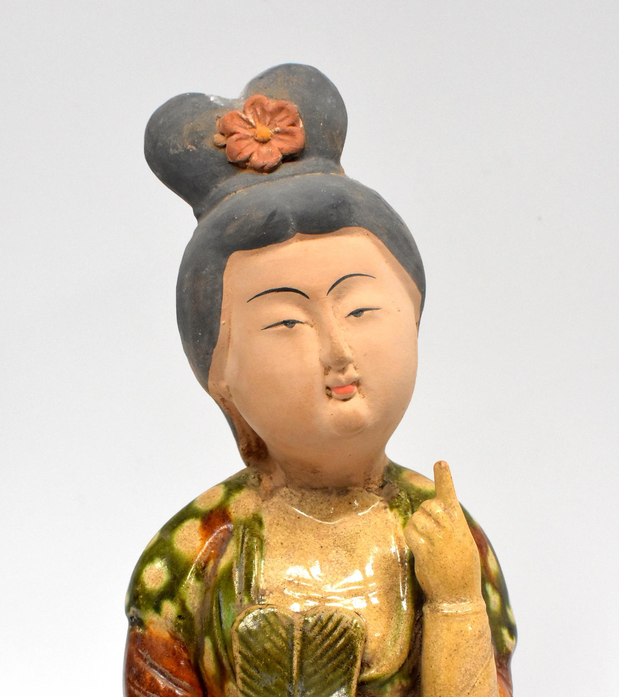 A beautiful terracotta court lady in the Chinese Tang dynasty San Cai style. The figure is modelled standing holding a green 