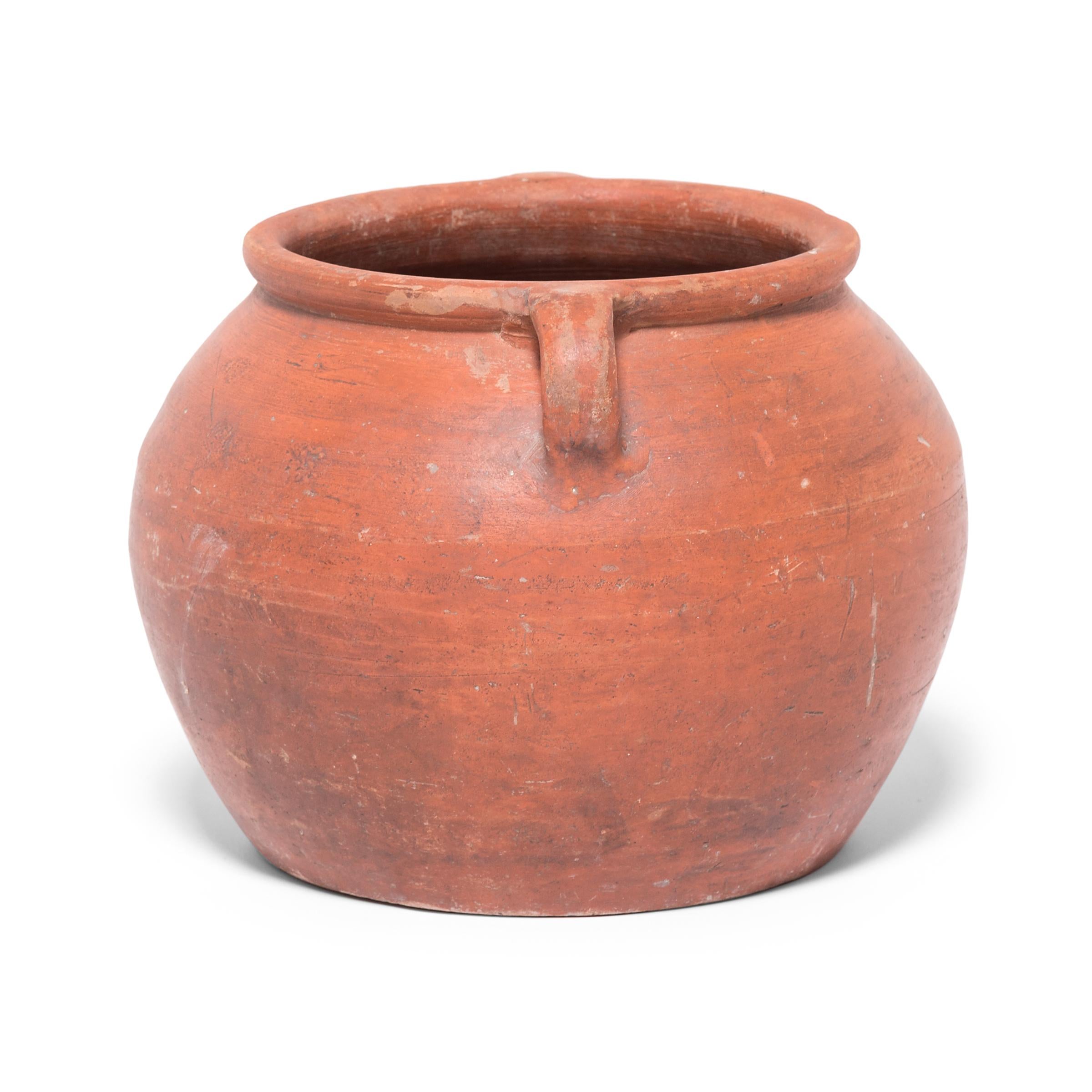 Based on vessels fired in ancient Chinese kilns, this jar's perfect proportions haven't changed much since the Bronze Age. Keeping in the tradition of its predecessors, this early 20th century ceramic vessel is glazed with a slip of red clay,