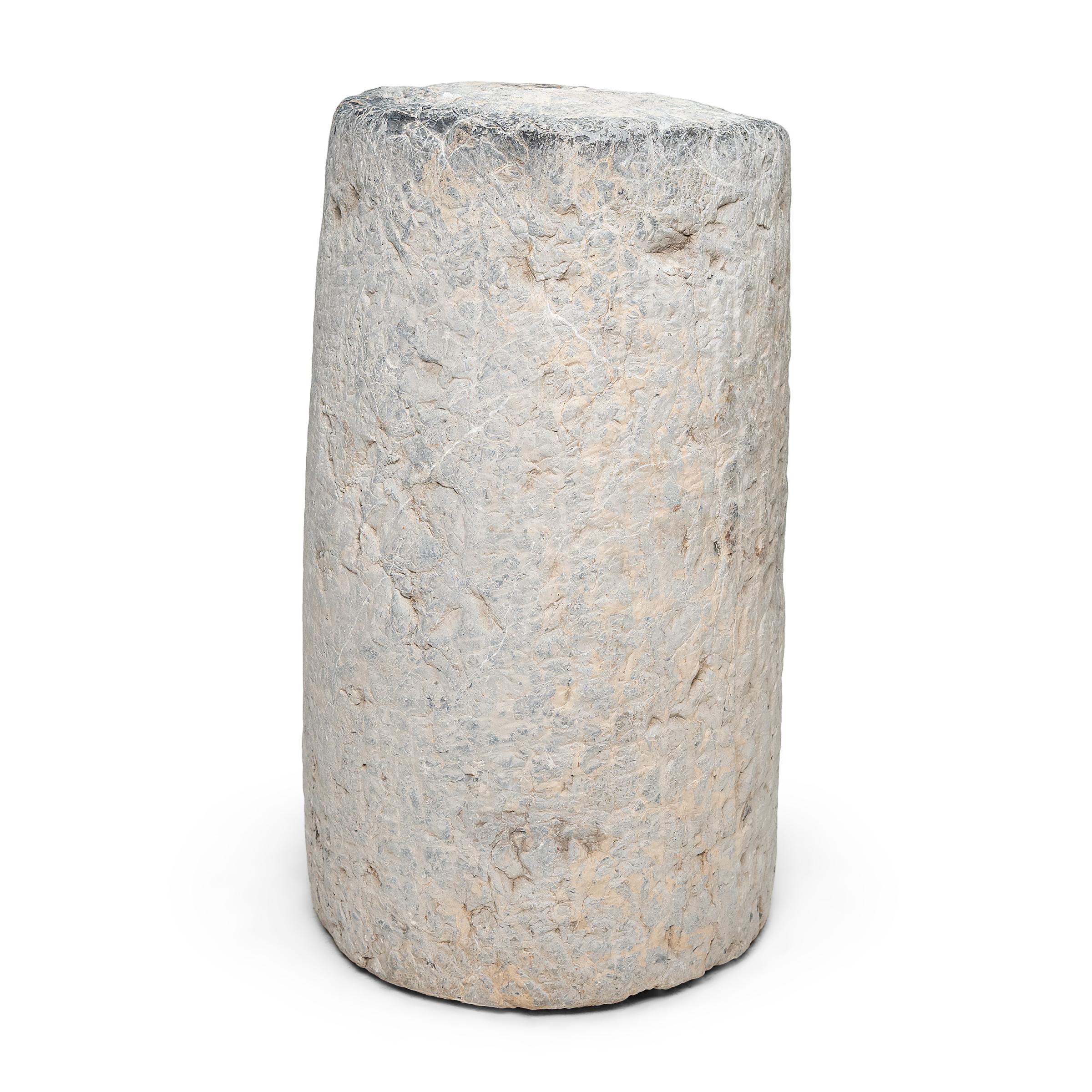 This low stone pedestal is an early 19th-century mill stone or roller stone, used for threshing grain on a farm in China's Shanxi province. The heavy stone would have been would have been pulled across a grain harvest, by man or ox, to separate the