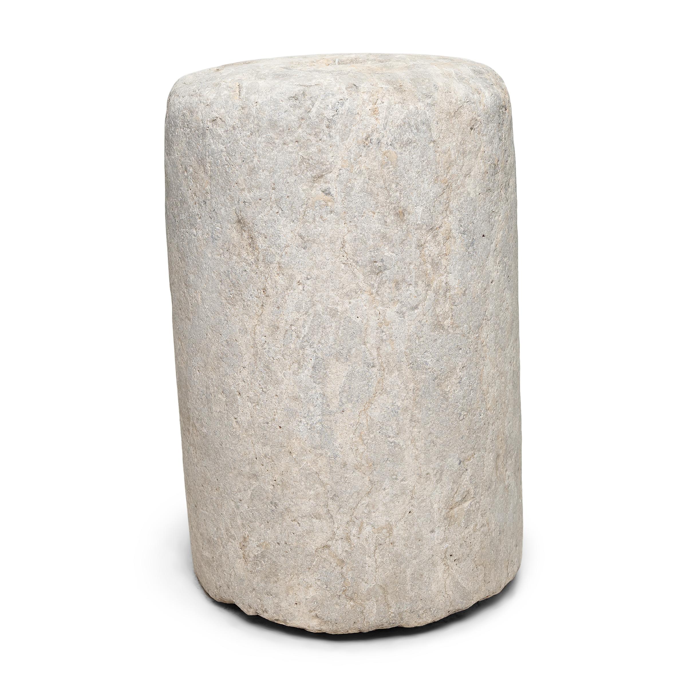 This low stone pedestal is an early 19th-century mill stone or roller stone, used for threshing grain on a farm in China's Shanxi province. The heavy stone would have been would have been pulled across a grain harvest, by man or ox, to separate the