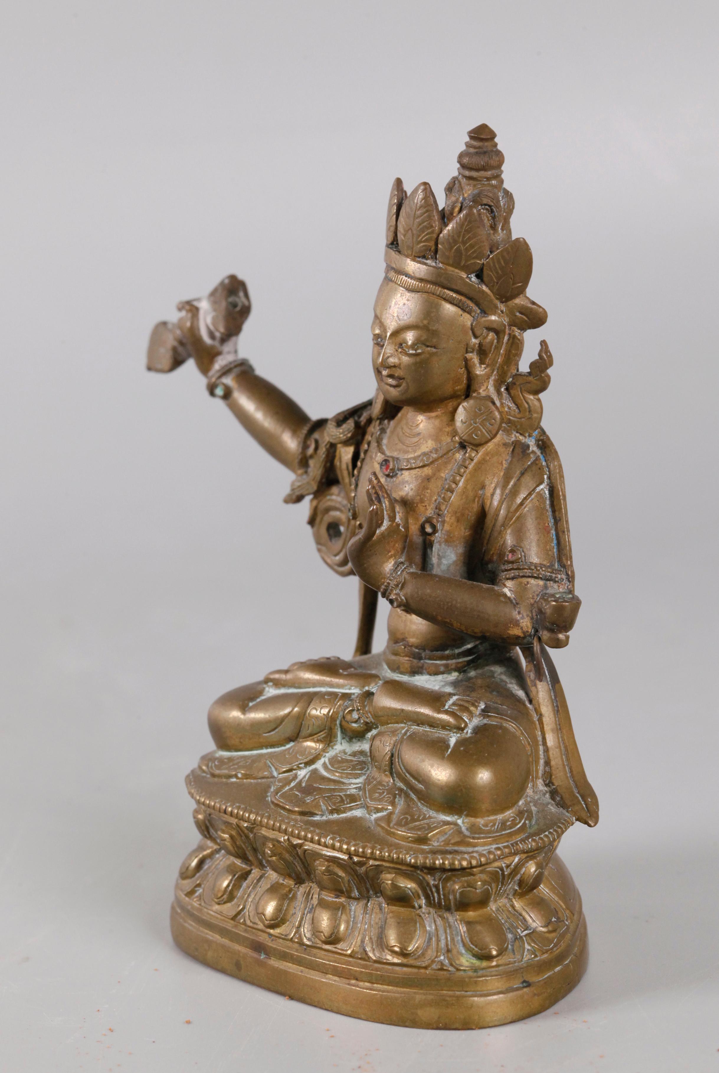 one hand is shown holding an ornament, and the other hand is in a typical Buddhist pose 