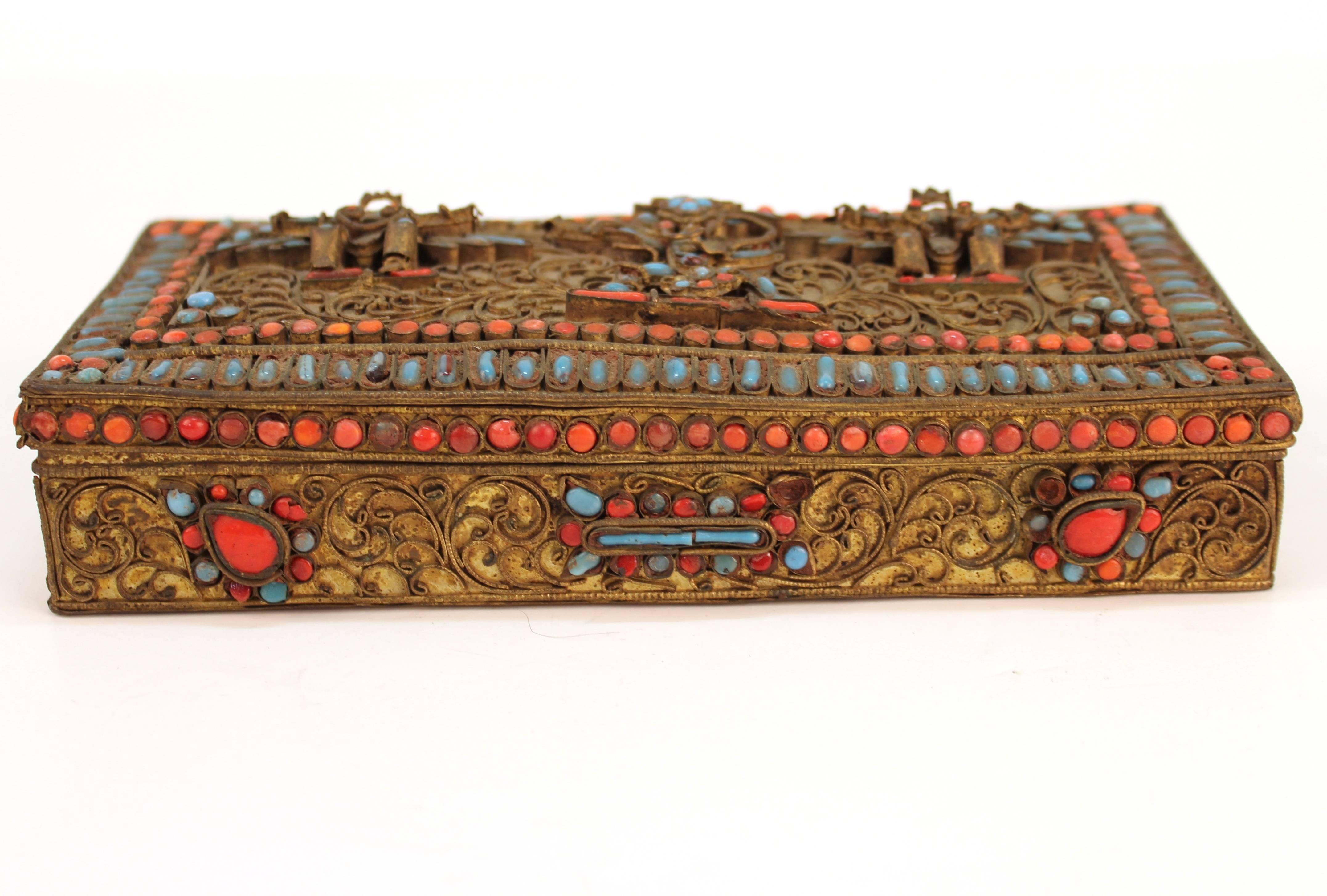 A Chinese-Tibetan brass box with turquoise and coral inlay and filigree figures of Vishnu and Garuda birds on the cover lid. In good vintage condition with age appropriate wear and patina, with some missing inlay pieces.
