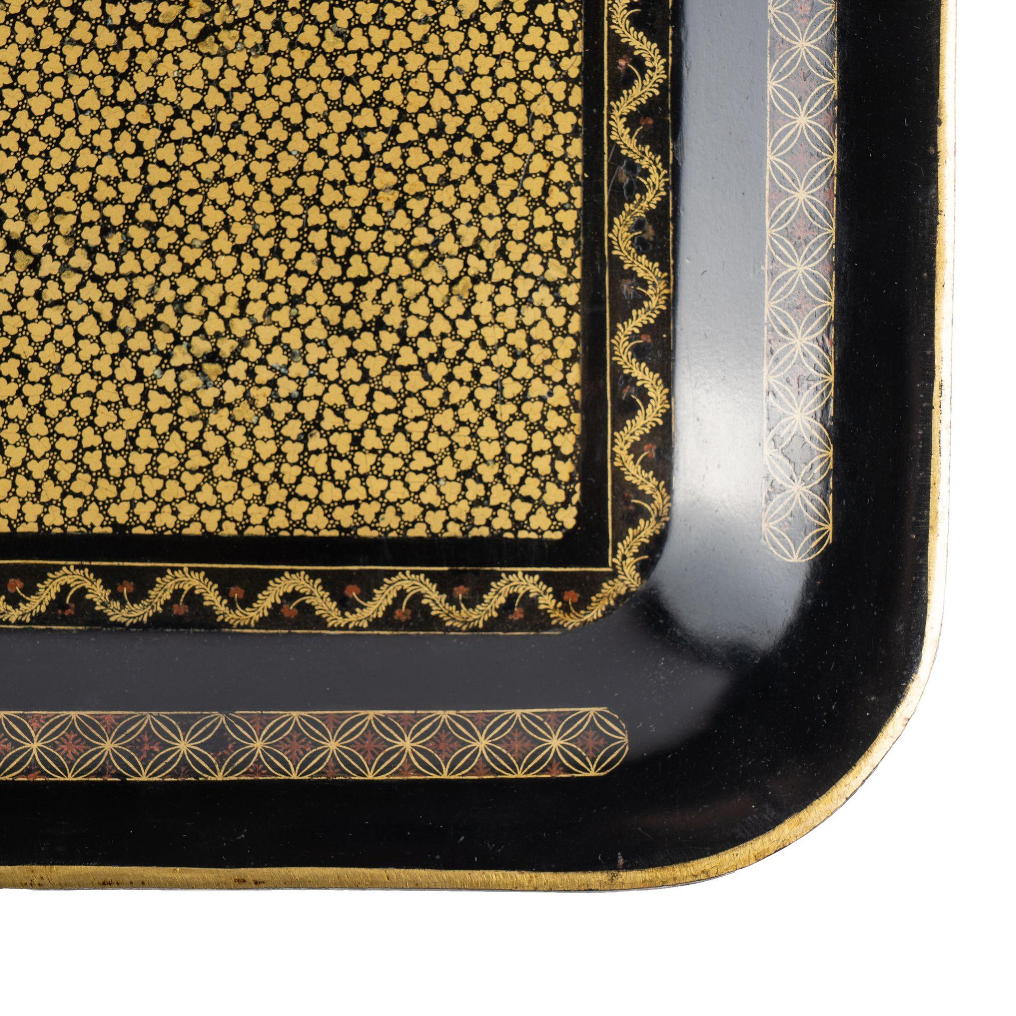 Stark gemustertes Teetablett aus chinesischem Tole. Der Boden des Tabletts wird von einem vergoldeten Feldmuster dominiert, das von einem wellenförmigen Banddekor eingefasst ist und an allen vier Seiten von einem geometrischen Muster flankiert wird.